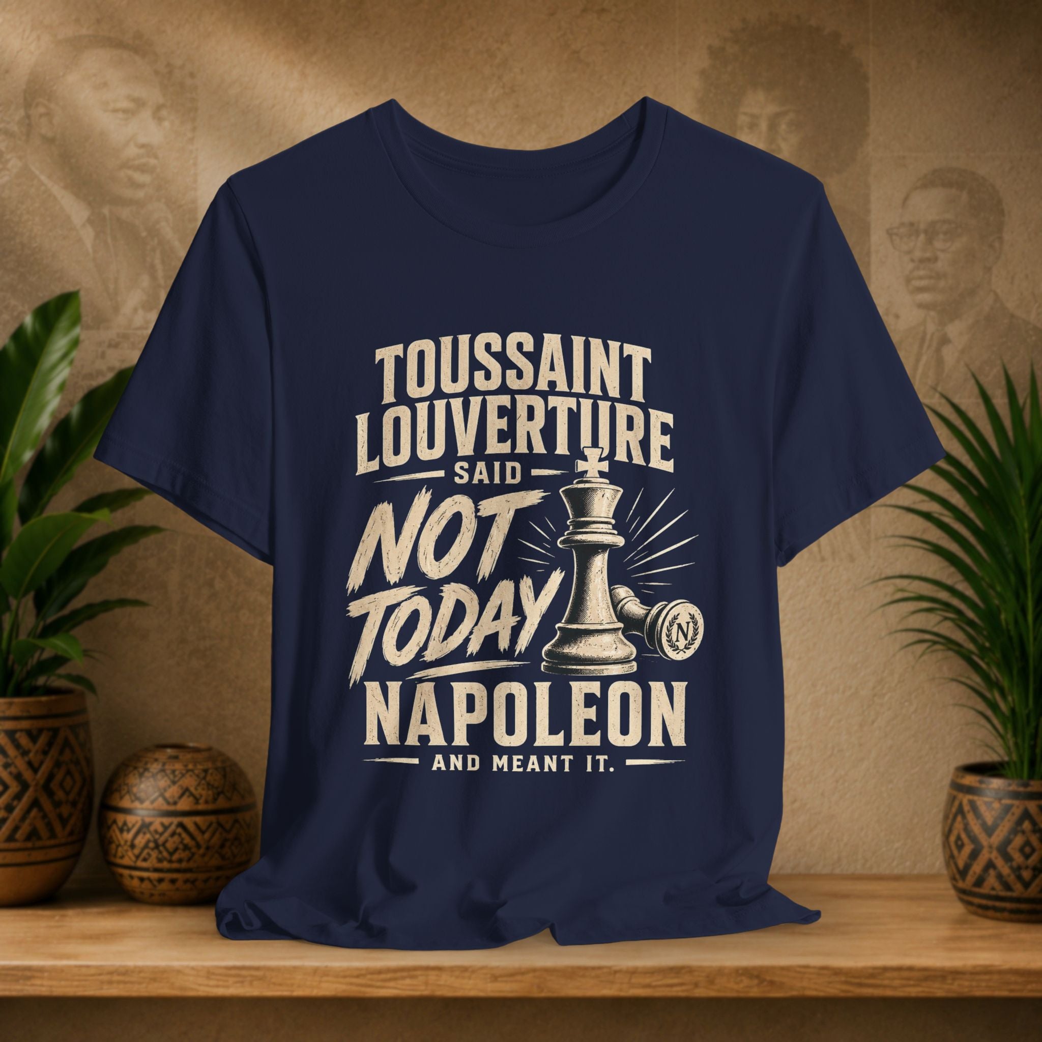Navy blue t-shirt with historical quote design on a wooden surface with plants and a textured wall background.