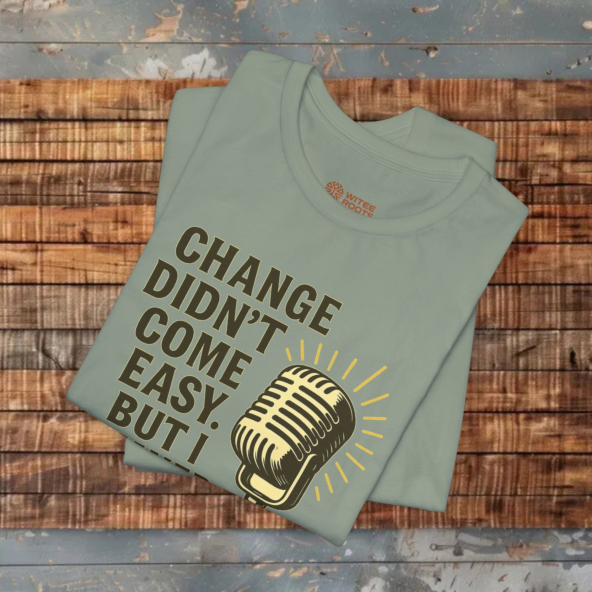 Folded green t-shirt with a microphone graphic and text on a wooden surface