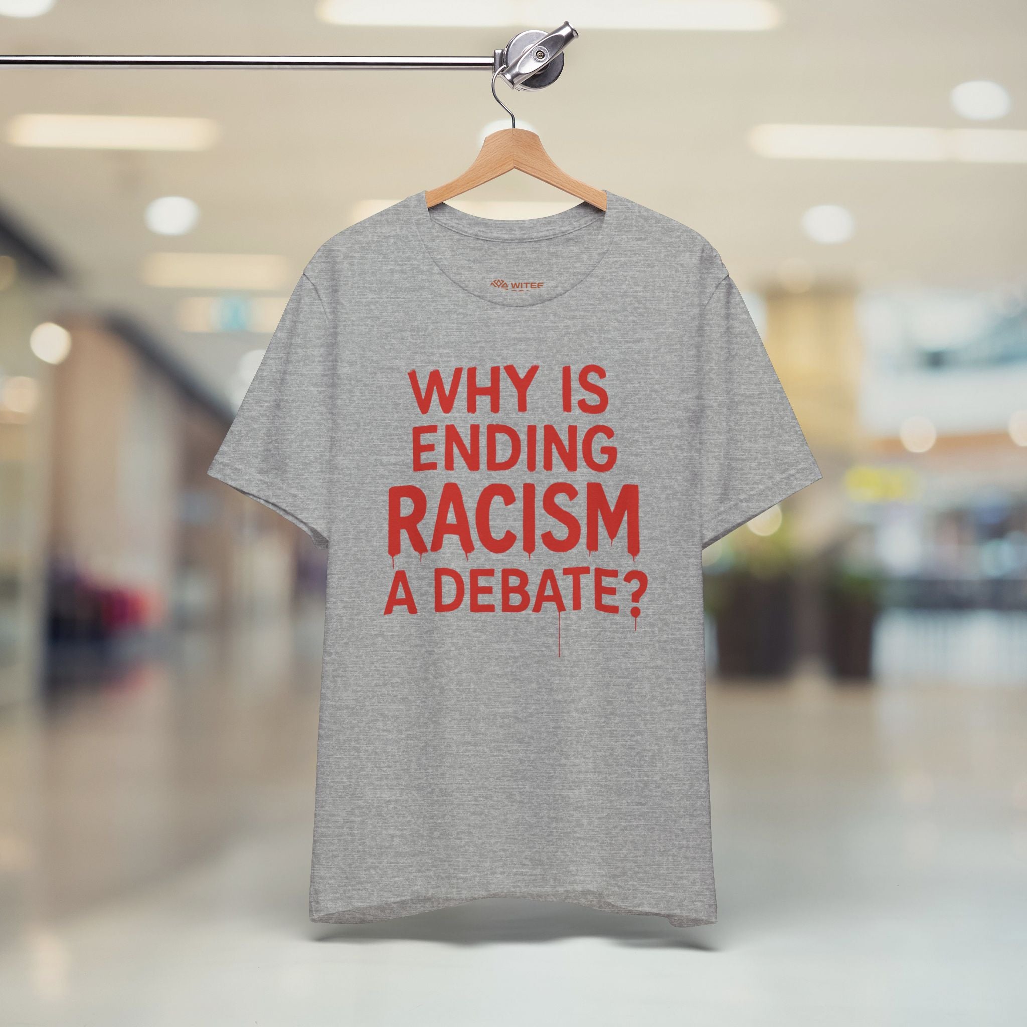 Gray t-shirt with red text on a hanger in a store setting