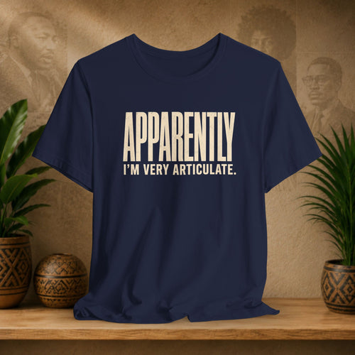 Navy blue t-shirt with white text 'APPROPRIATELY I'M VERY ARTICULATE' on a wooden surface with plants and a textured wall background.