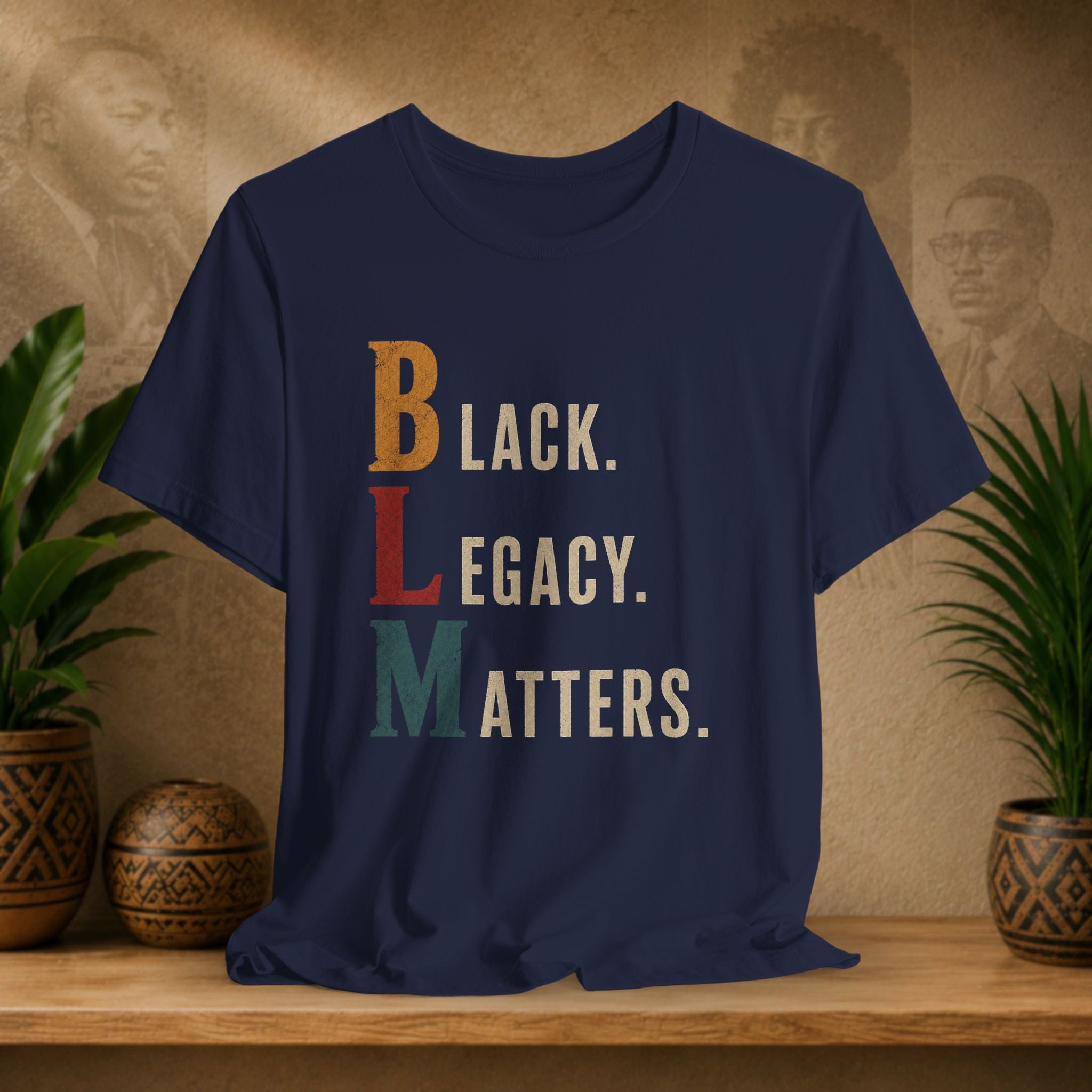 A navy blue graphic t-shirt displayed on a wooden shelf, featuring the text 'BLACK. LEGACY.