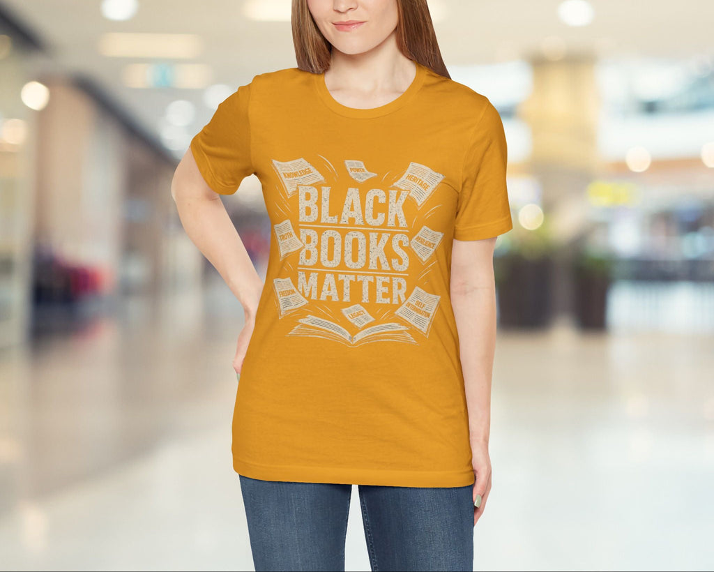 Woman wearing a mustard yellow t-shirt with 'Black Books Matter' text in a mall setting