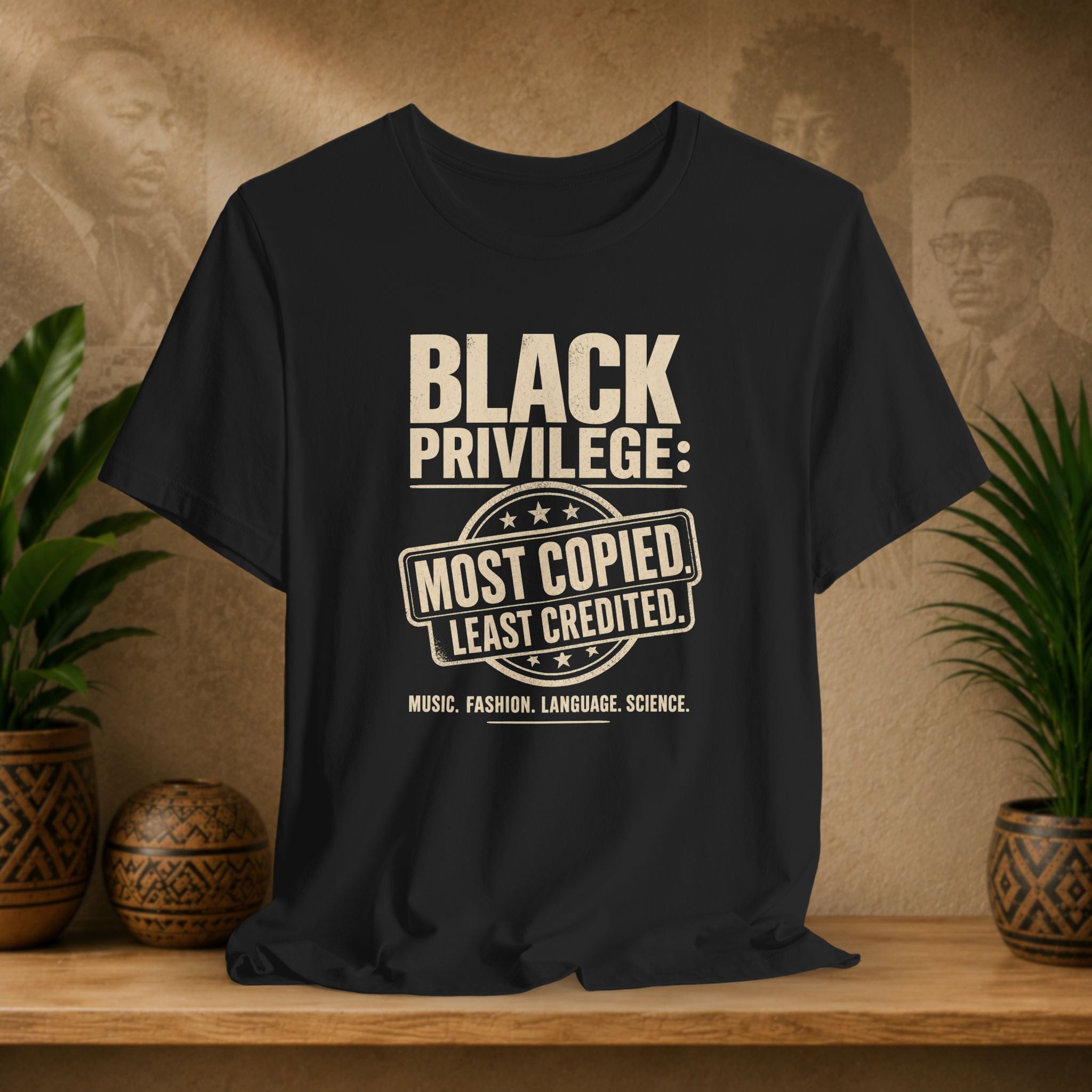 Black t-shirt with white text on a wooden surface with plants and a blurred background