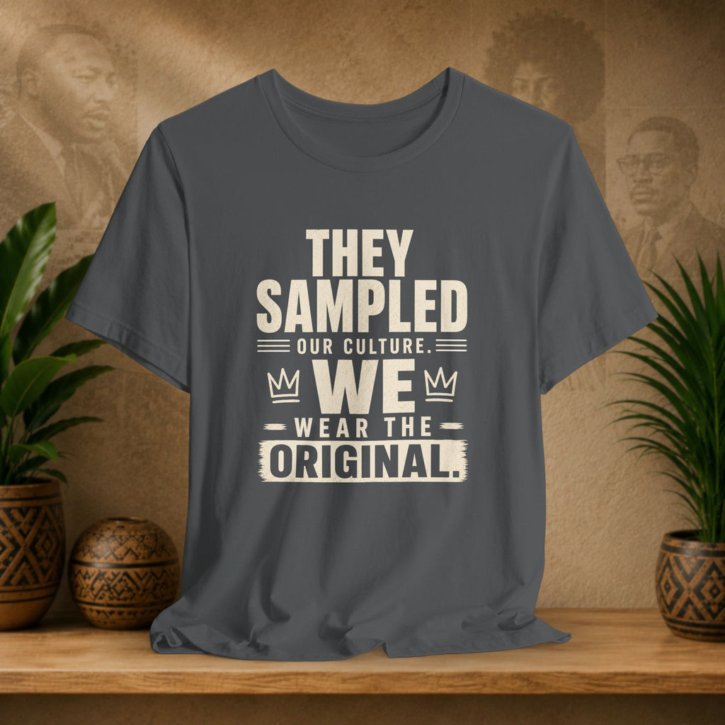 Gray t-shirt with text on a wooden surface with plants and decorative items in the background