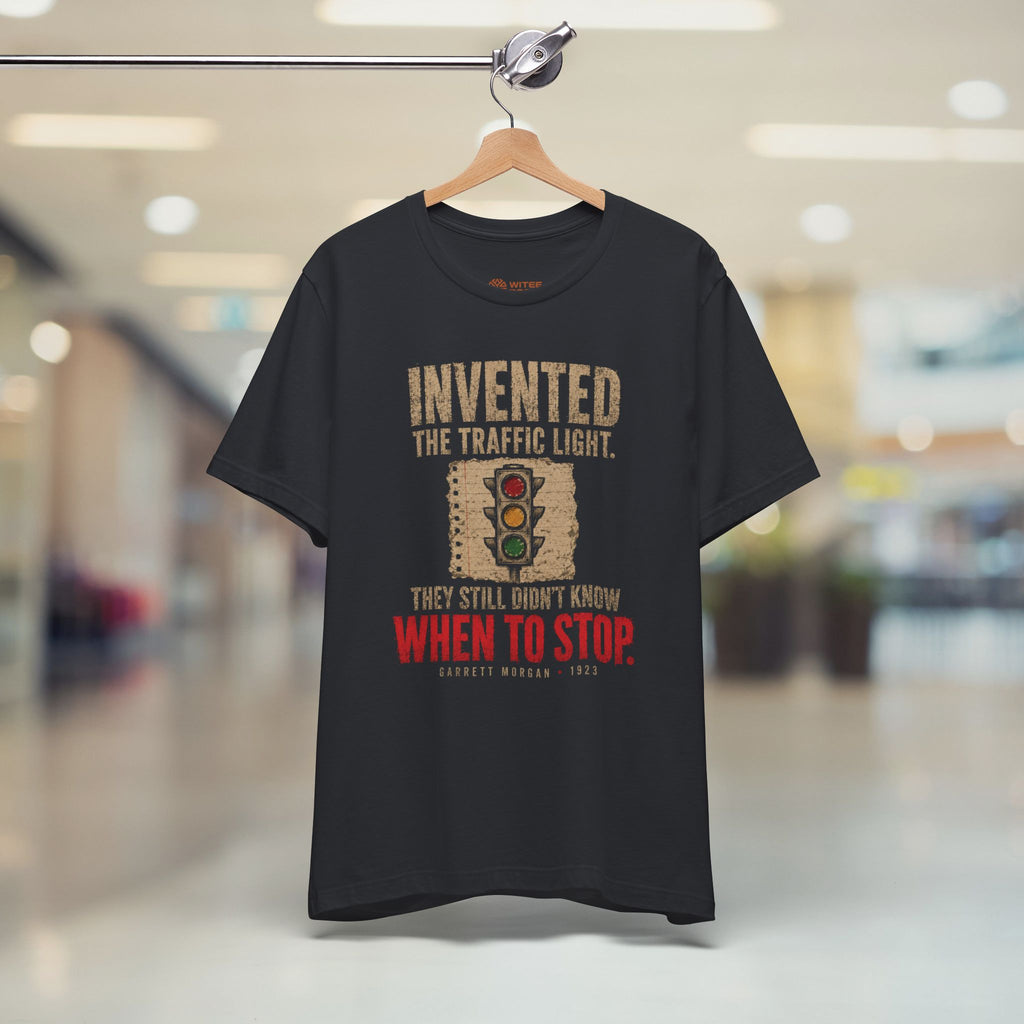 Black t-shirt with humorous traffic light design on a hanger in a store.