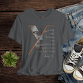 Gray t-shirt with graphic design and text, placed on a wooden surface with jeans and shoes.