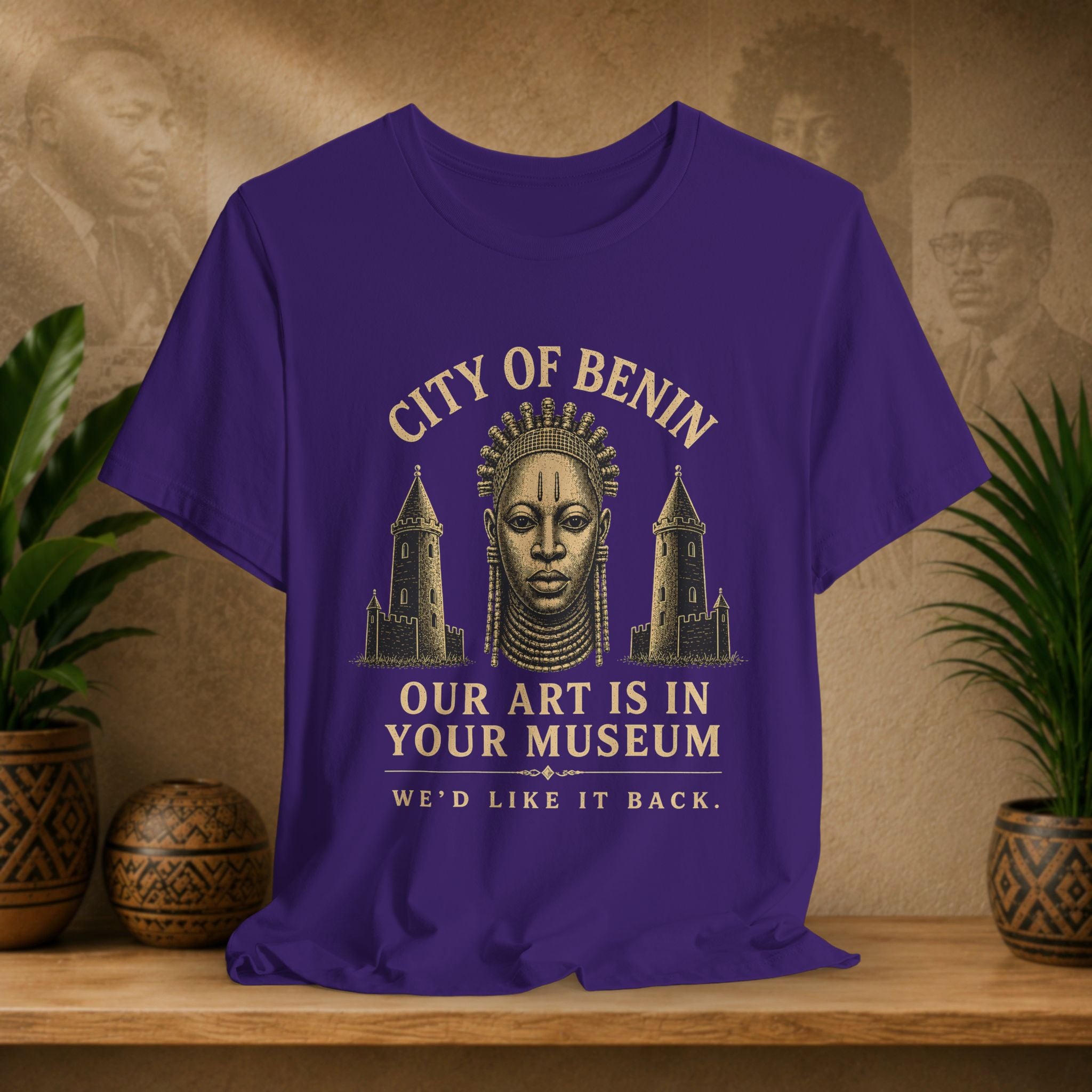 Purple t-shirt with graphic design and text on a wooden surface with plants and decorative items.