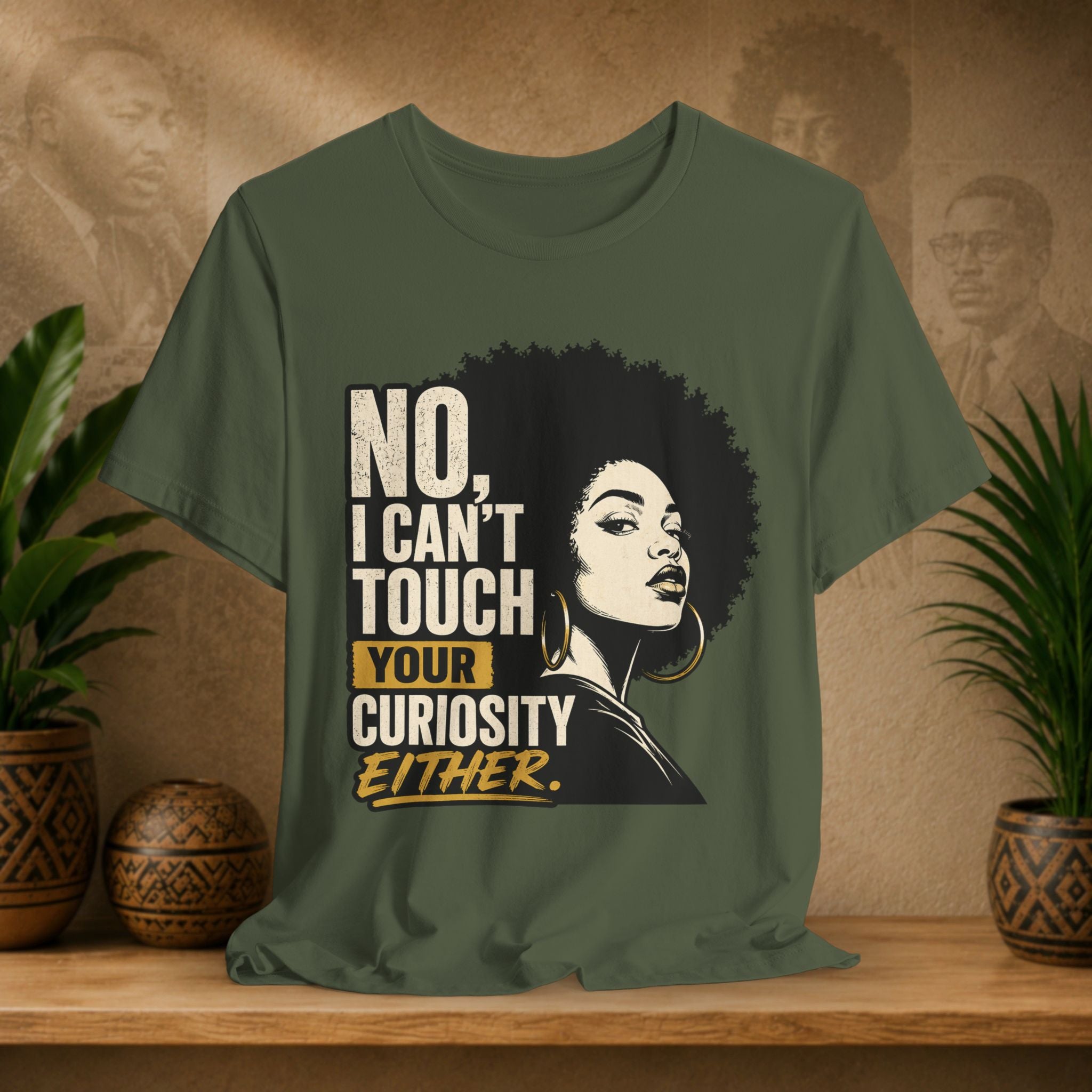 Green t-shirt with a graphic of a woman with an afro and text on a wooden surface with plants and a textured wall in the background.