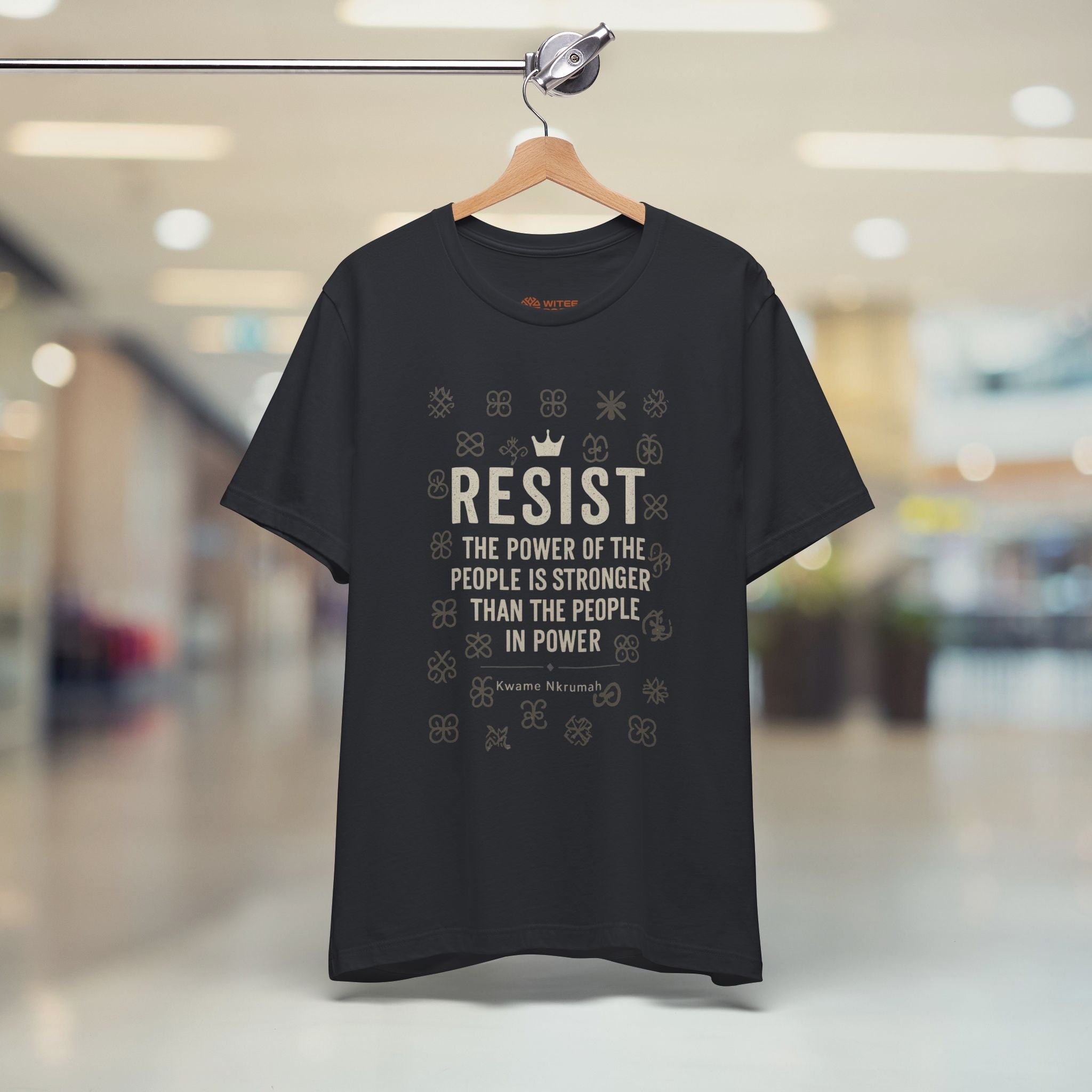 Black t-shirt with 'RESIST' text on a hanger in a store setting