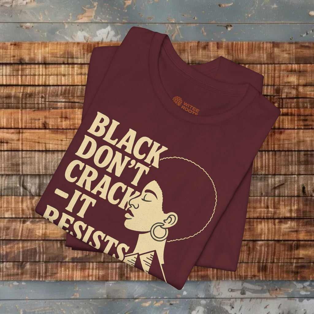 Maroon t-shirt with graphic design and text on a wooden surface