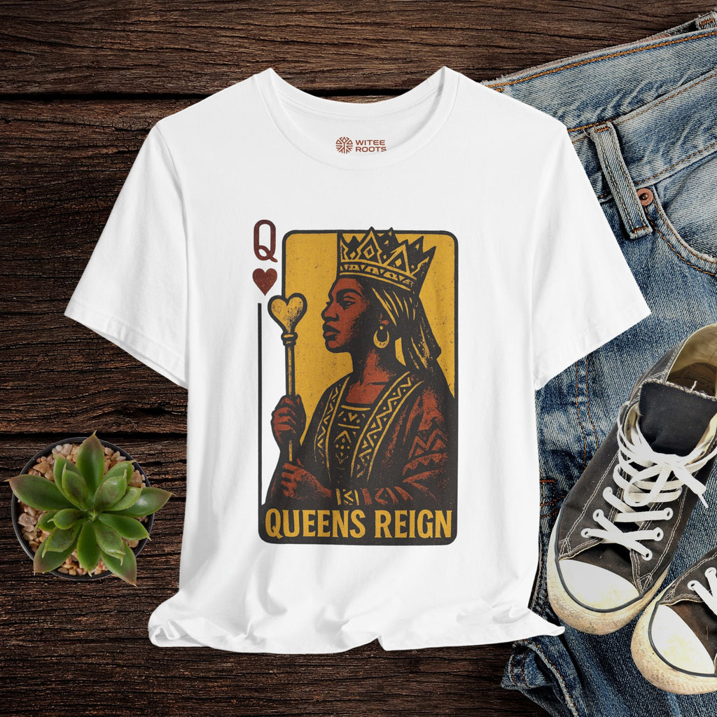 White t-shirt with 'Queens Reign' design on a wooden surface with jeans and sneakers.