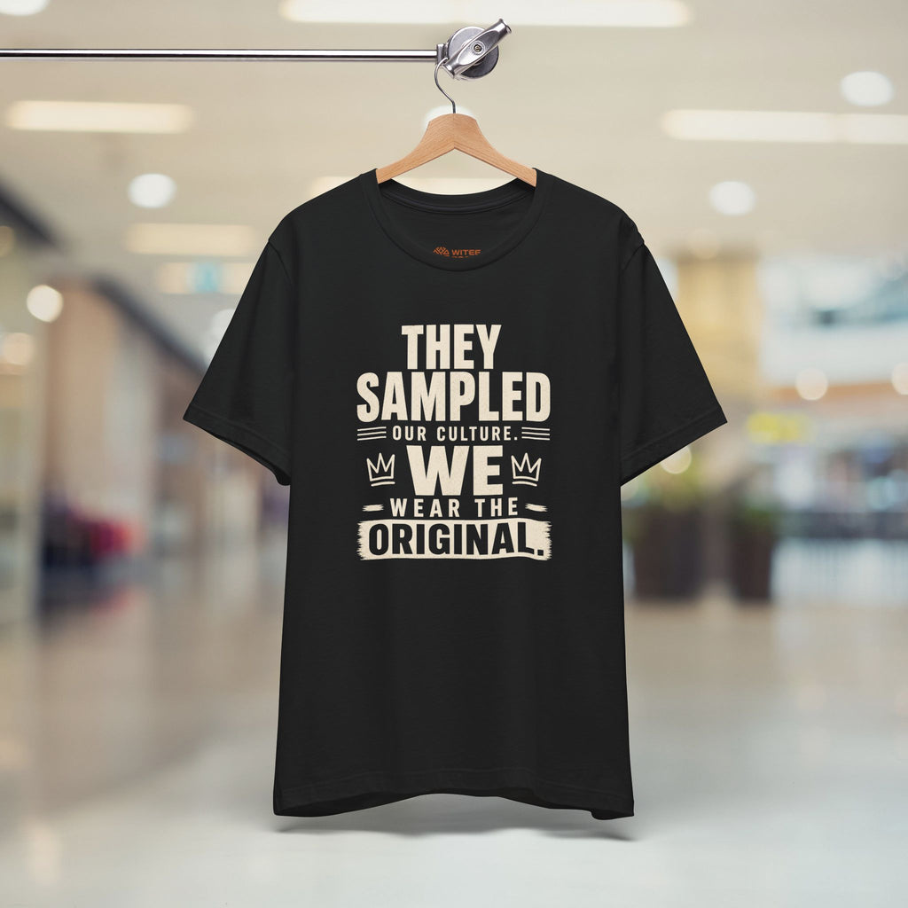 Black t-shirt with white text on a hanger in a store setting