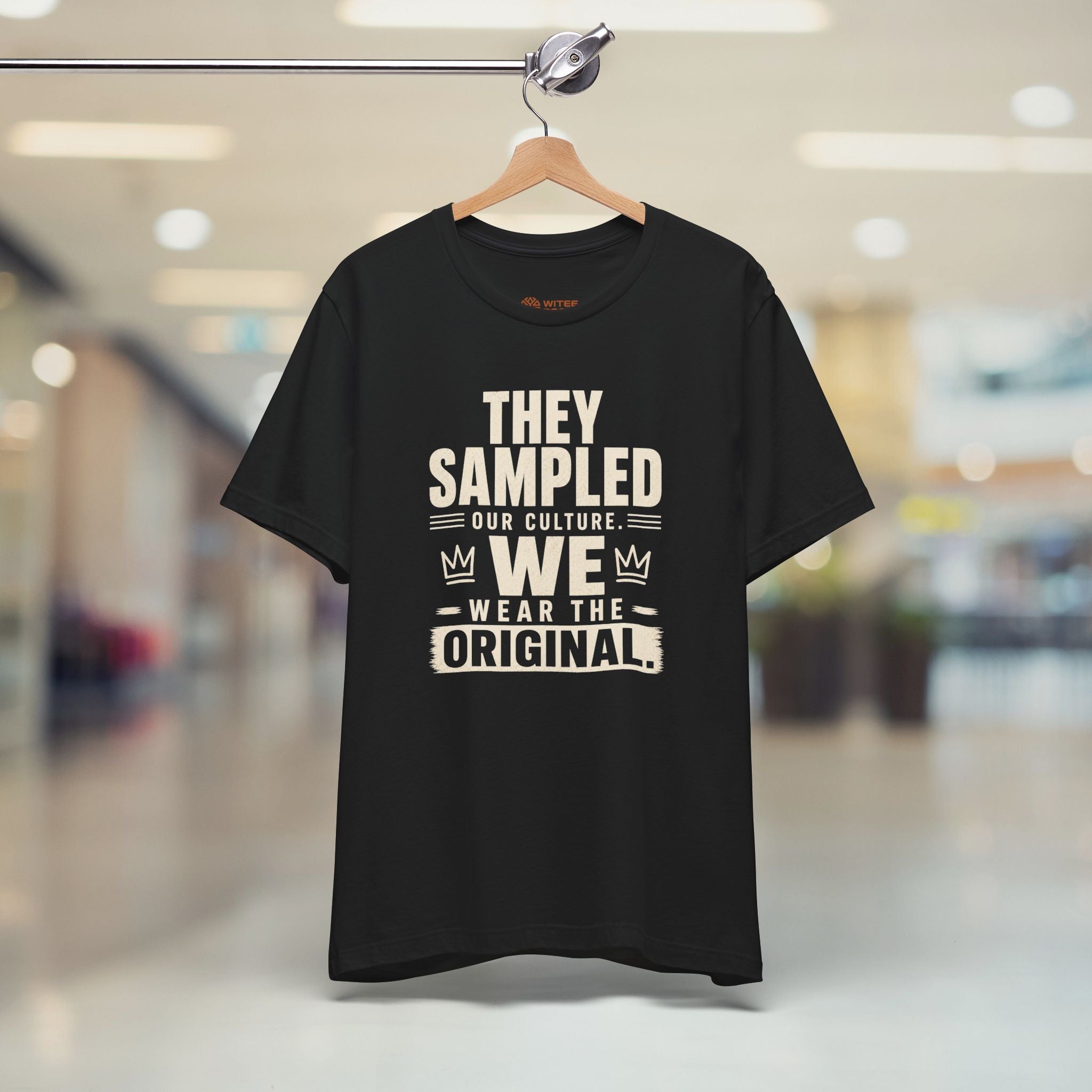 Black t-shirt with white text on a hanger in a store setting