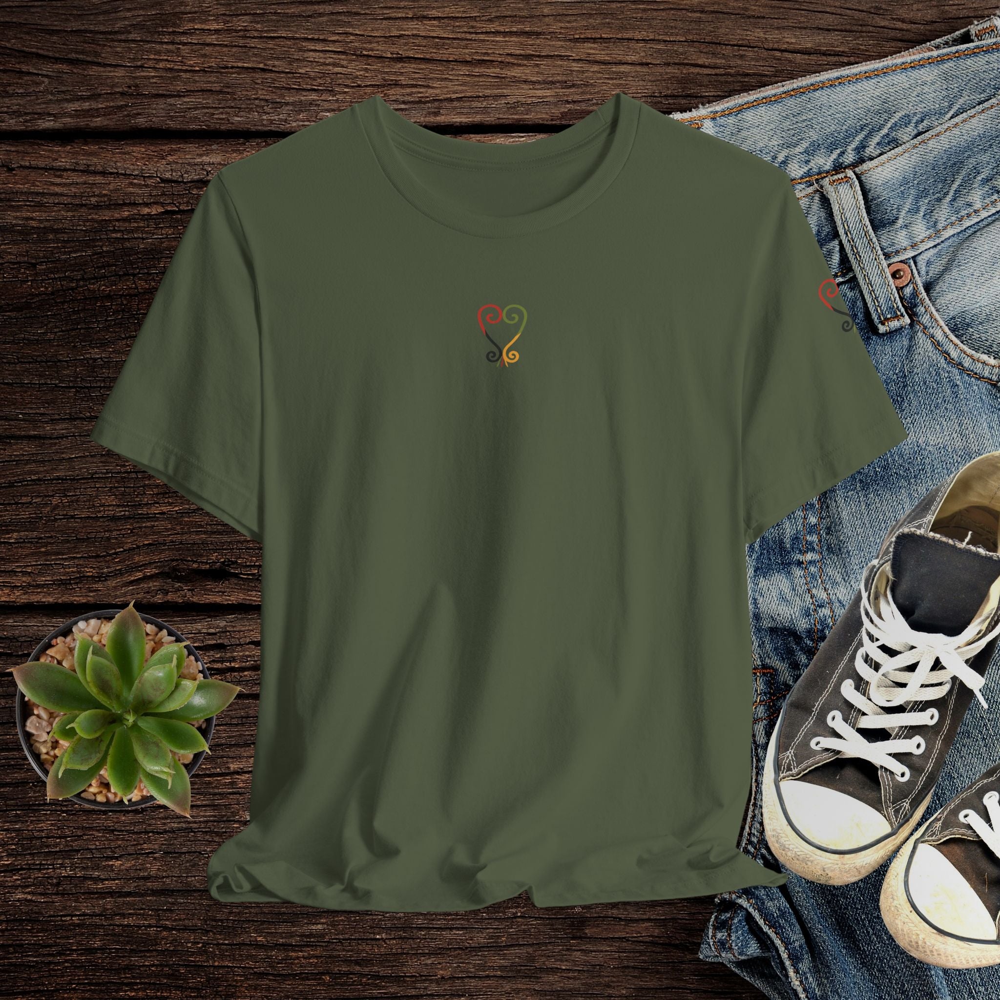 Green t-shirt with a logo on a wooden surface with jeans and shoes.