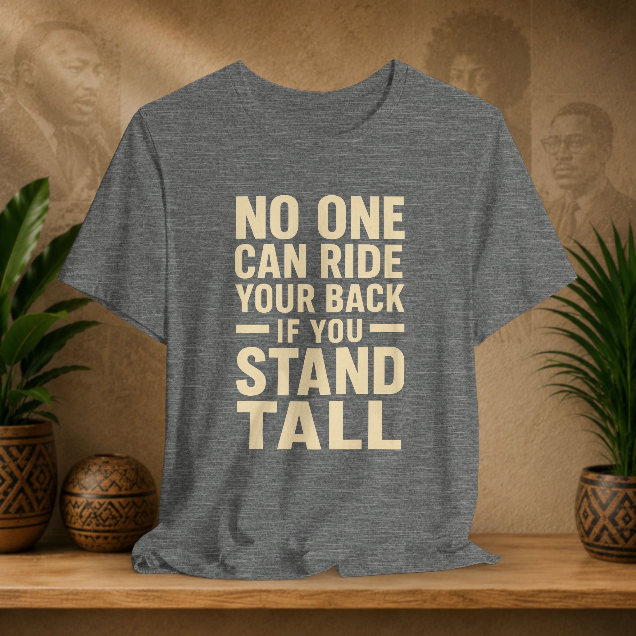 Grey t-shirt with motivational quote on a wooden surface with decorative plants and background.