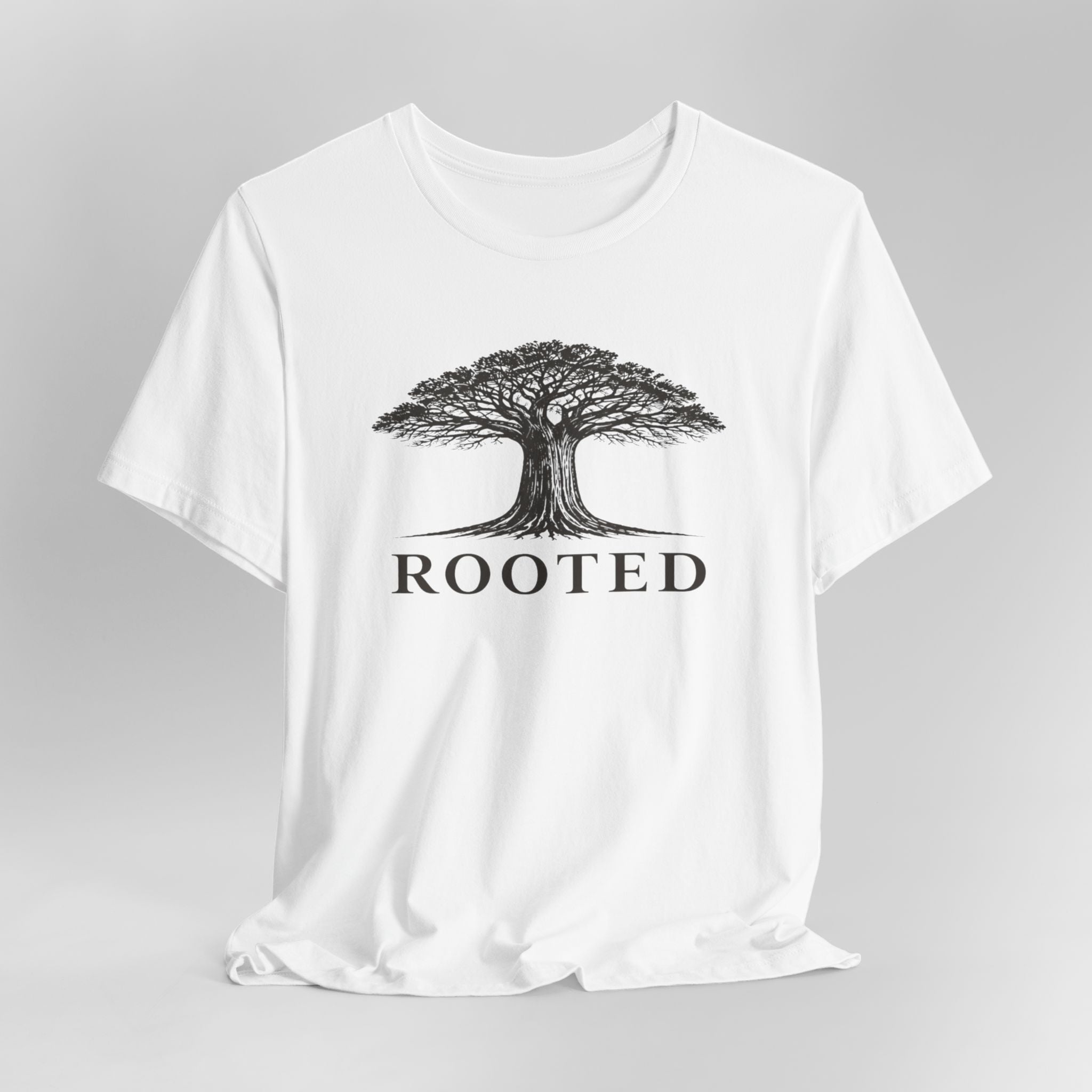 White t-shirt with a tree graphic and 'ROOTED' text on a gray background