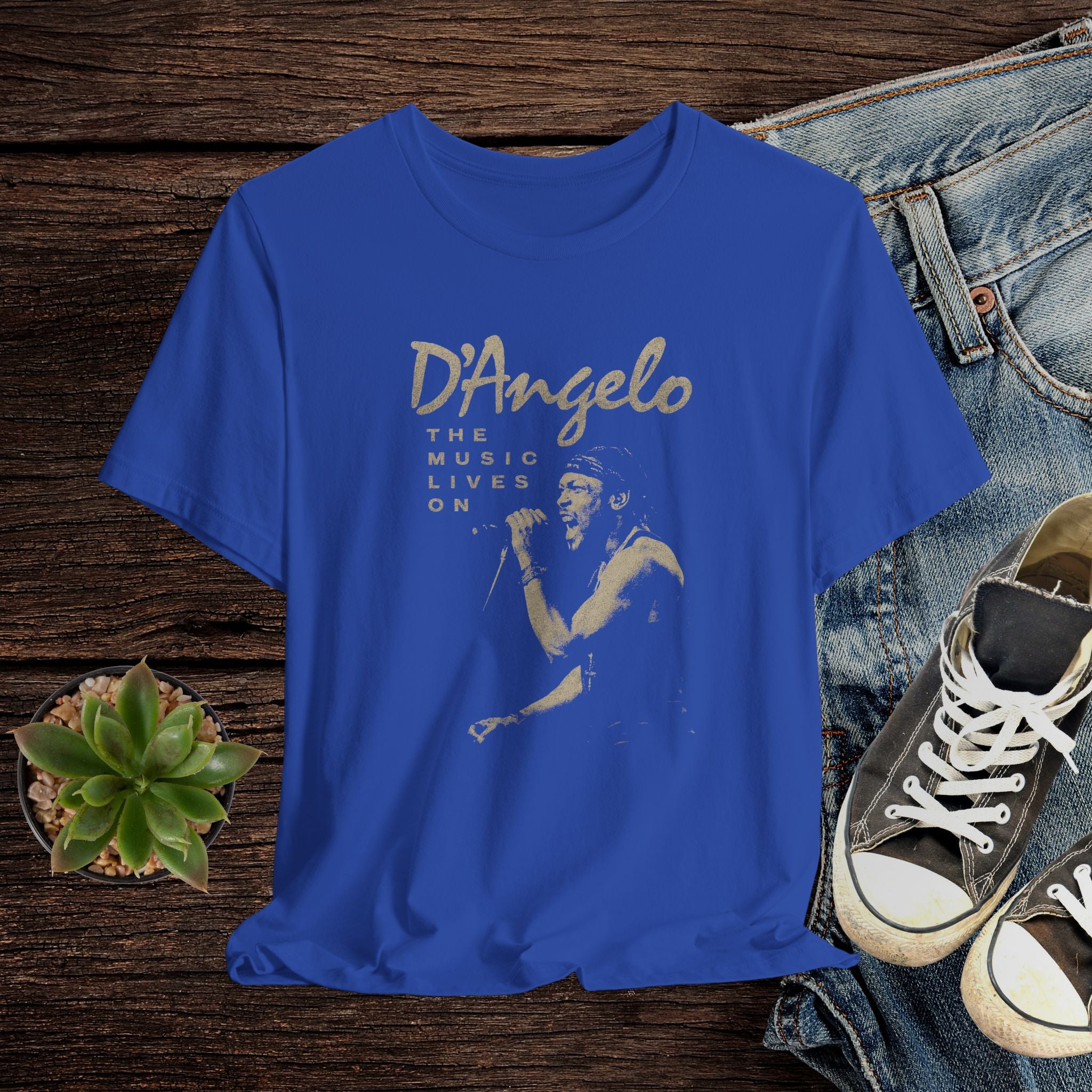 Blue t-shirt with D'Angelo graphic design on a wooden surface with jeans and sneakers.