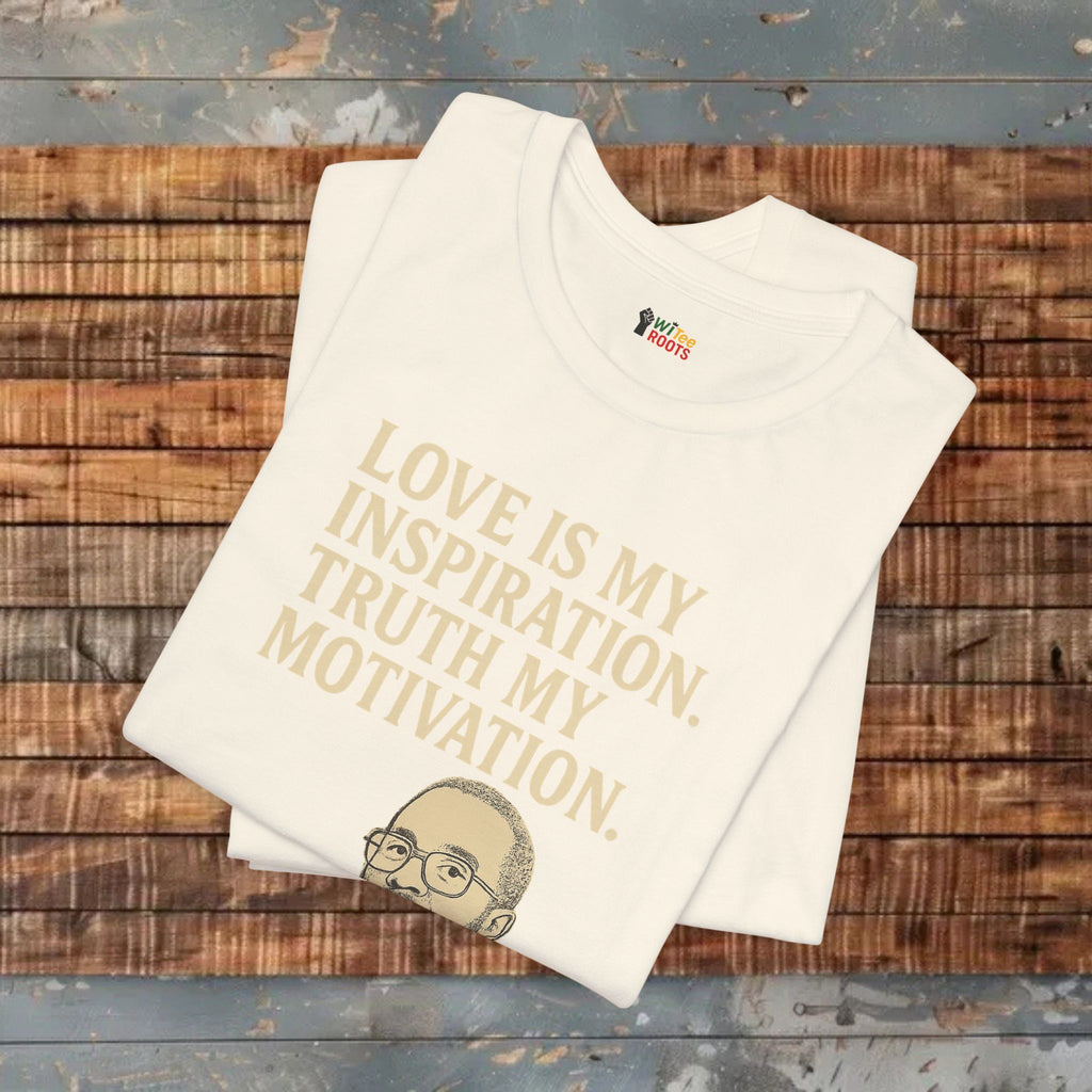 Beige t-shirt with gold text and a small graphic on a wooden surface