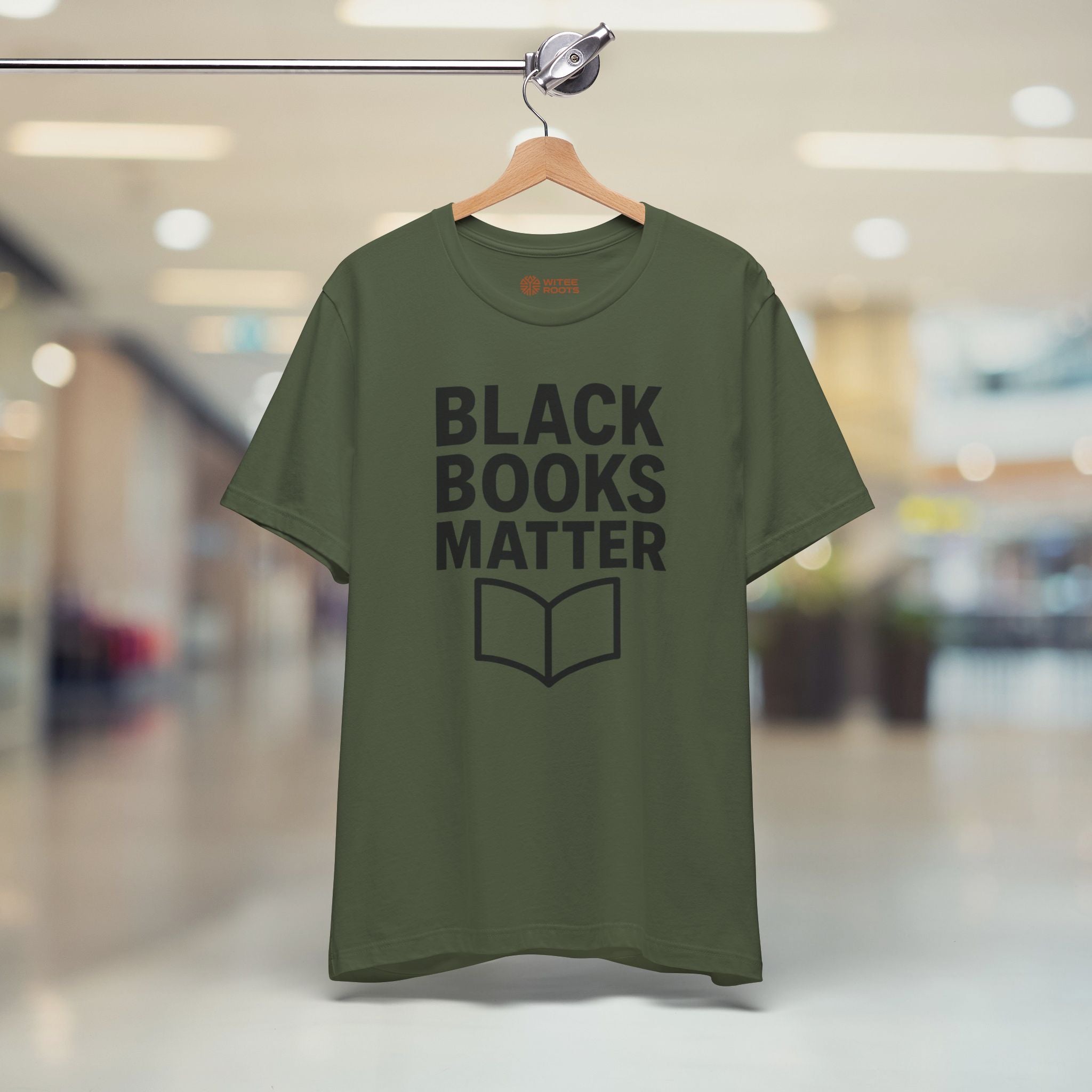 Green t-shirt with 'BLACK BOOKS MATTER' text on a hanger in a store setting