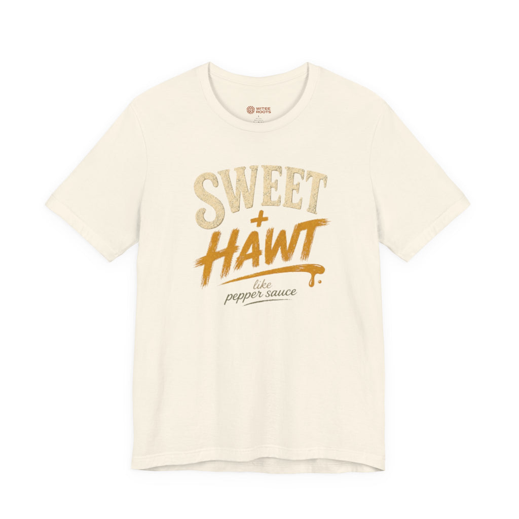 An off-white short-sleeve t-shirt with a graphic print on the front reading 'SWEET + HAWT like pepper sauce' in textured beige and orange lettering, displayed on a clean white background.