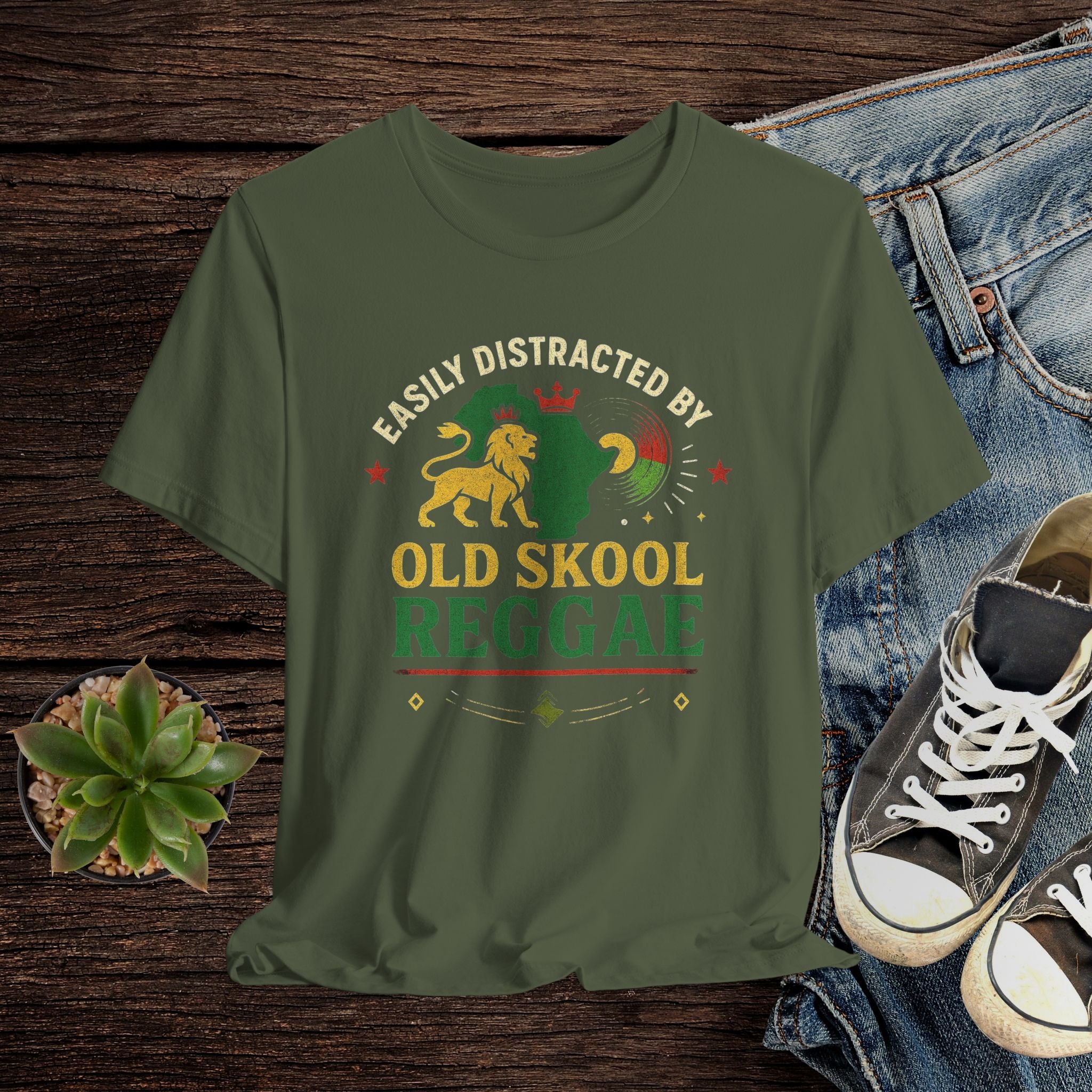 Green t-shirt with 'Old Skool Reggae' design on a wooden surface with jeans and sneakers.