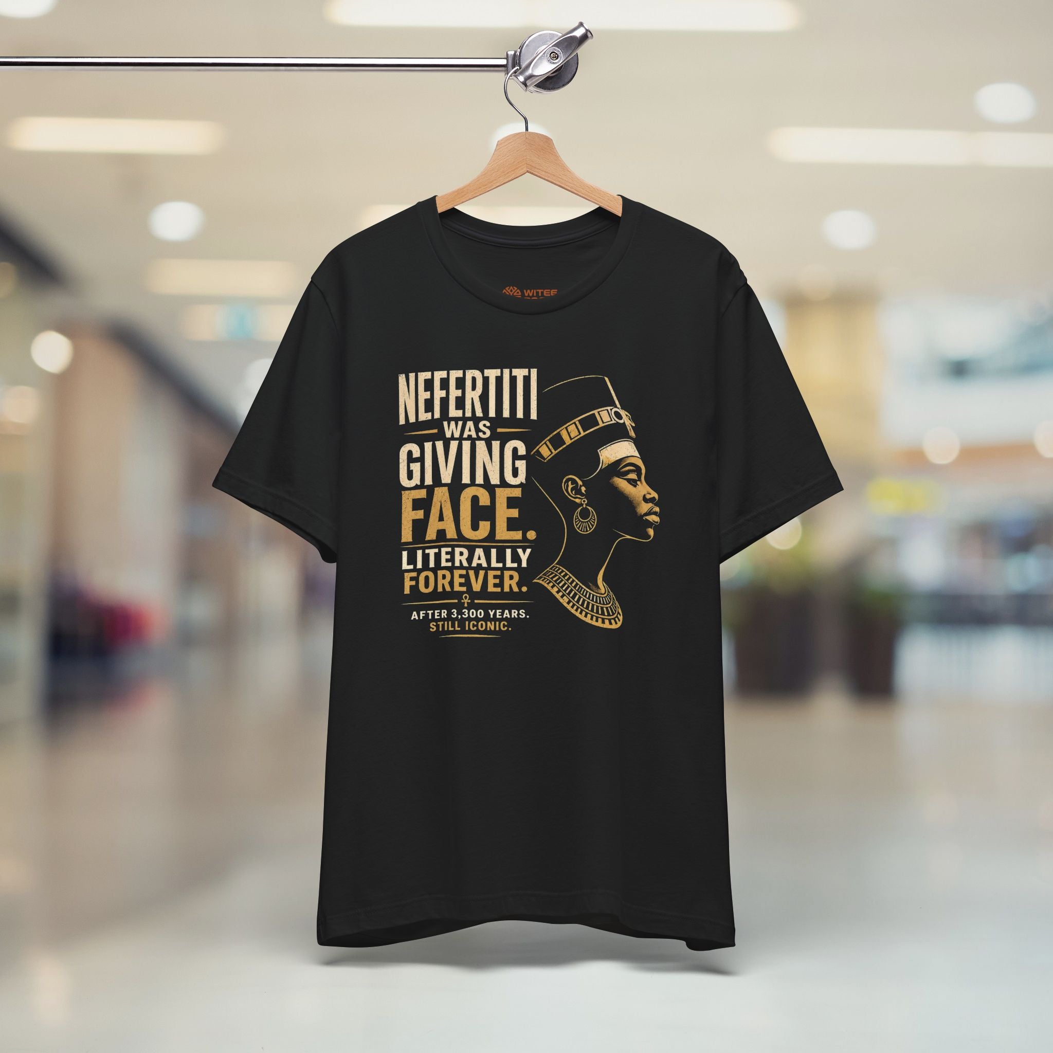 Black t-shirt with gold text and graphic of a woman on a hanger in a store.