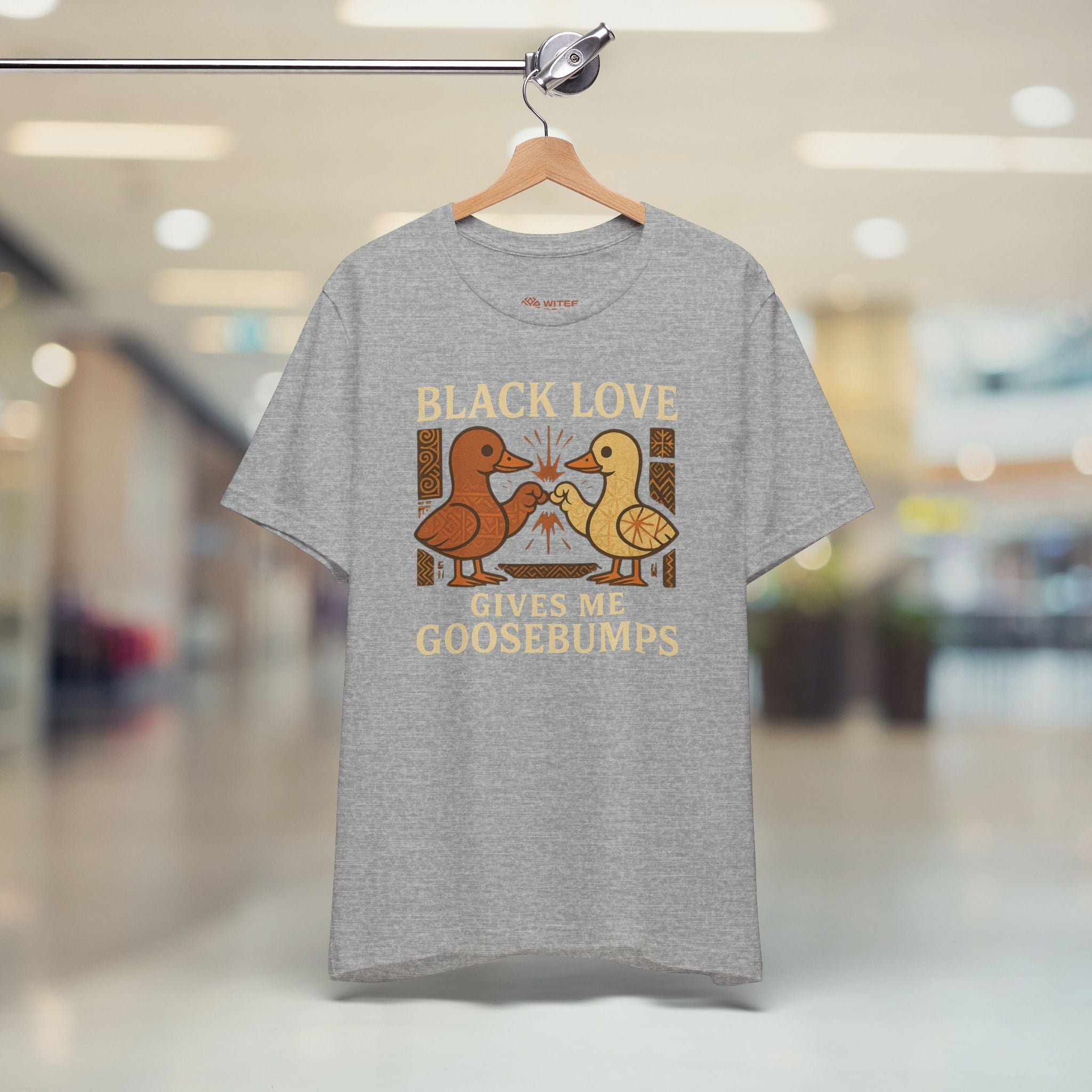 Gray t-shirt with 'Black Love Gives Me Goosebumps' graphic on a hanger in a store.