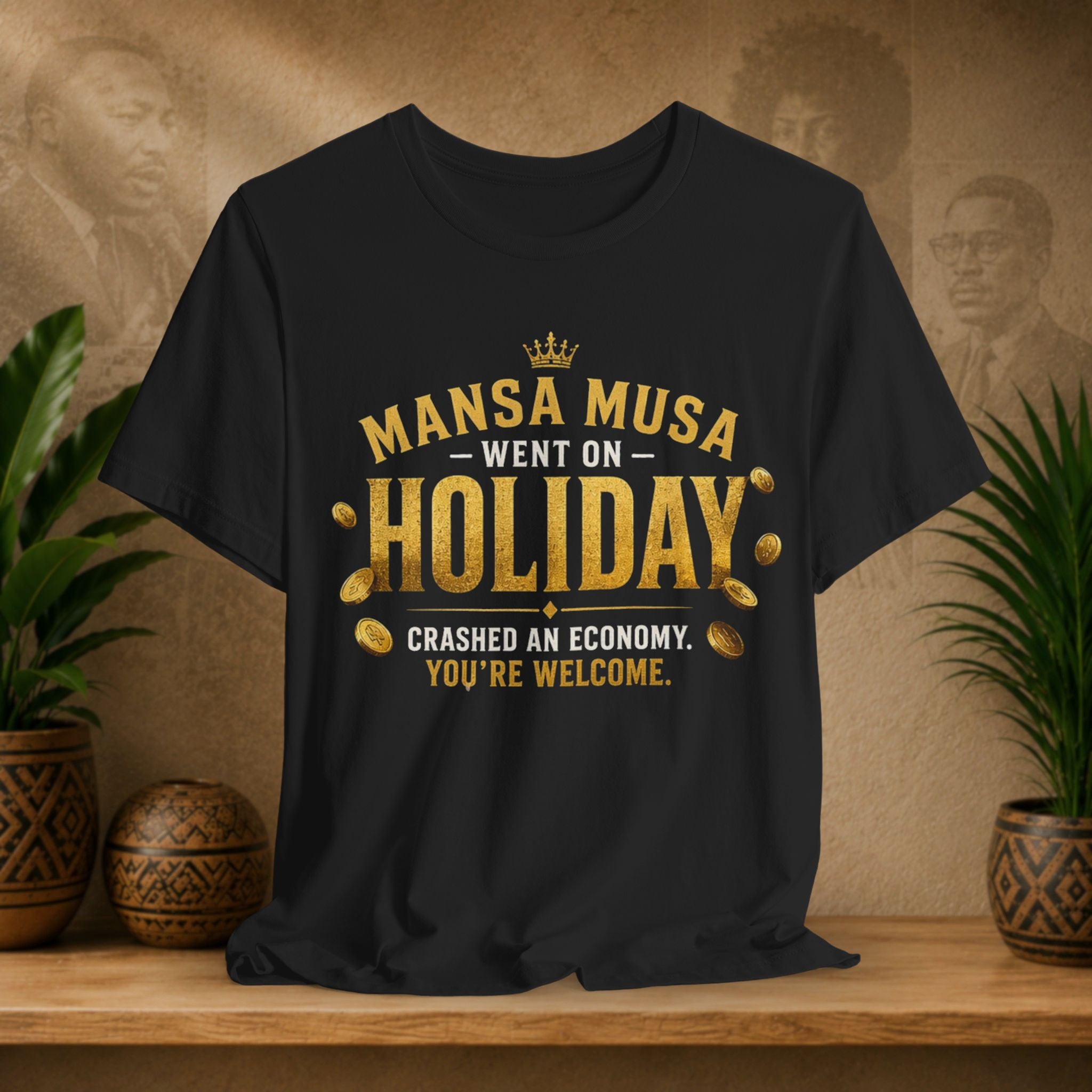 Black t-shirt with gold text on a wooden surface with plants and a textured wall background