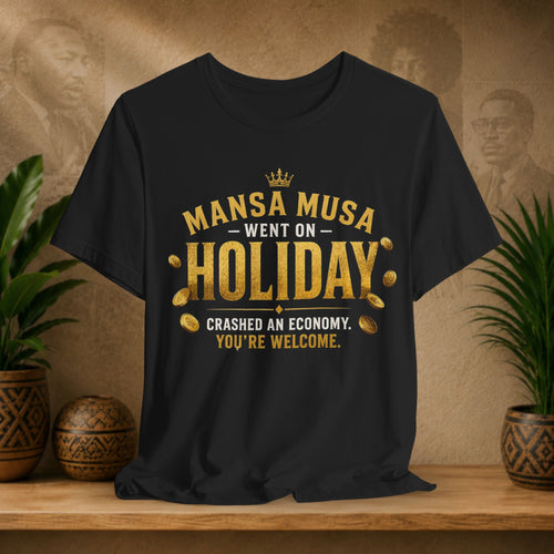 Black t-shirt with gold text on a wooden surface with plants and a textured wall background