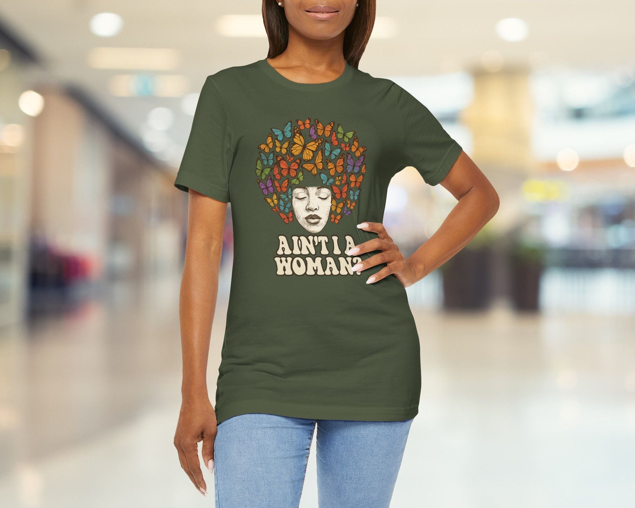 Woman wearing a green t-shirt with a graphic design and text in a blurred indoor setting