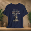 Navy blue t-shirt with a graphic of a woman in a crown and text on a wooden surface with plants.