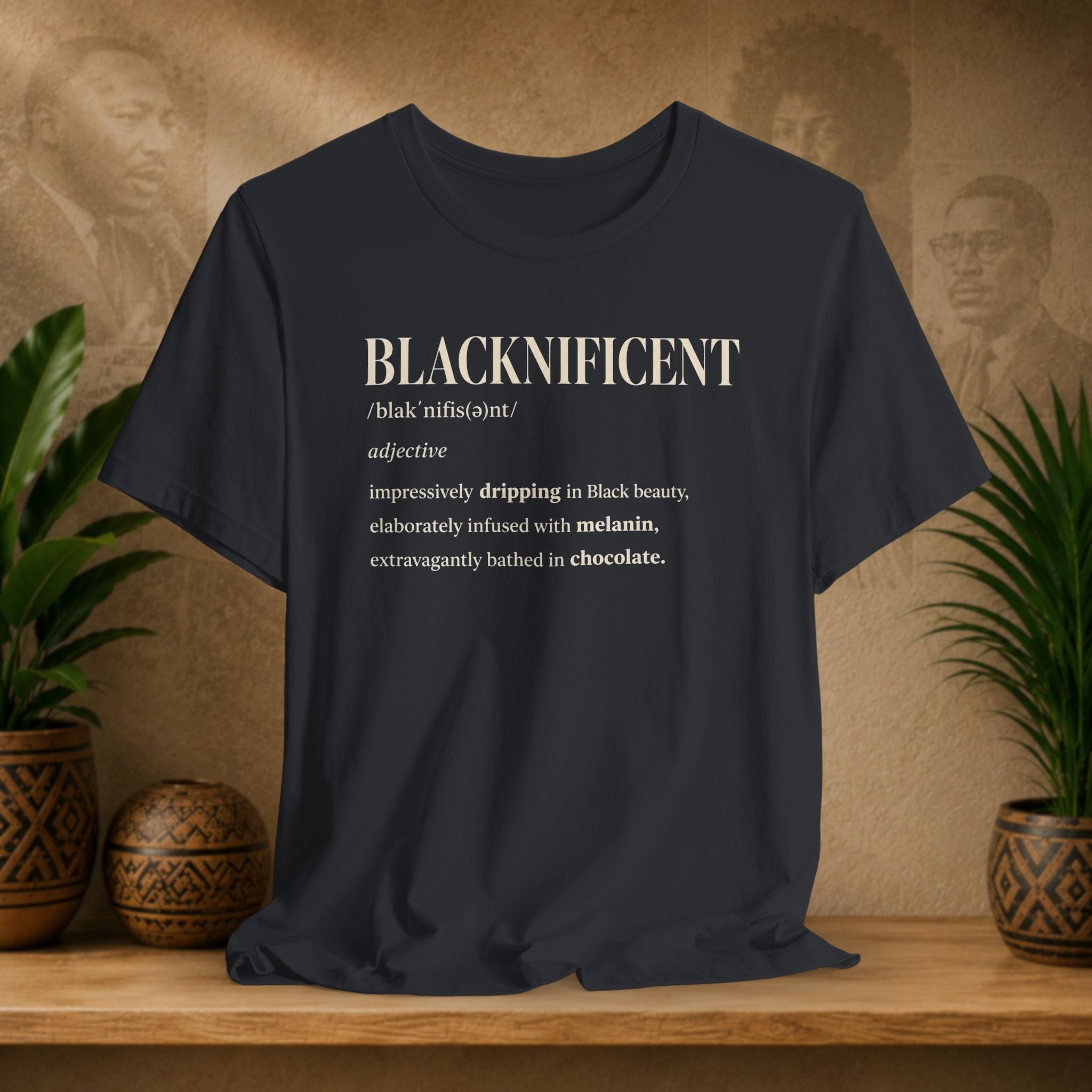 A black graphic t-shirt displayed on a wooden shelf. The shirt features a humorous dictionary-style definition of the word 'BLACKNIFICENT' in cream-colored text.