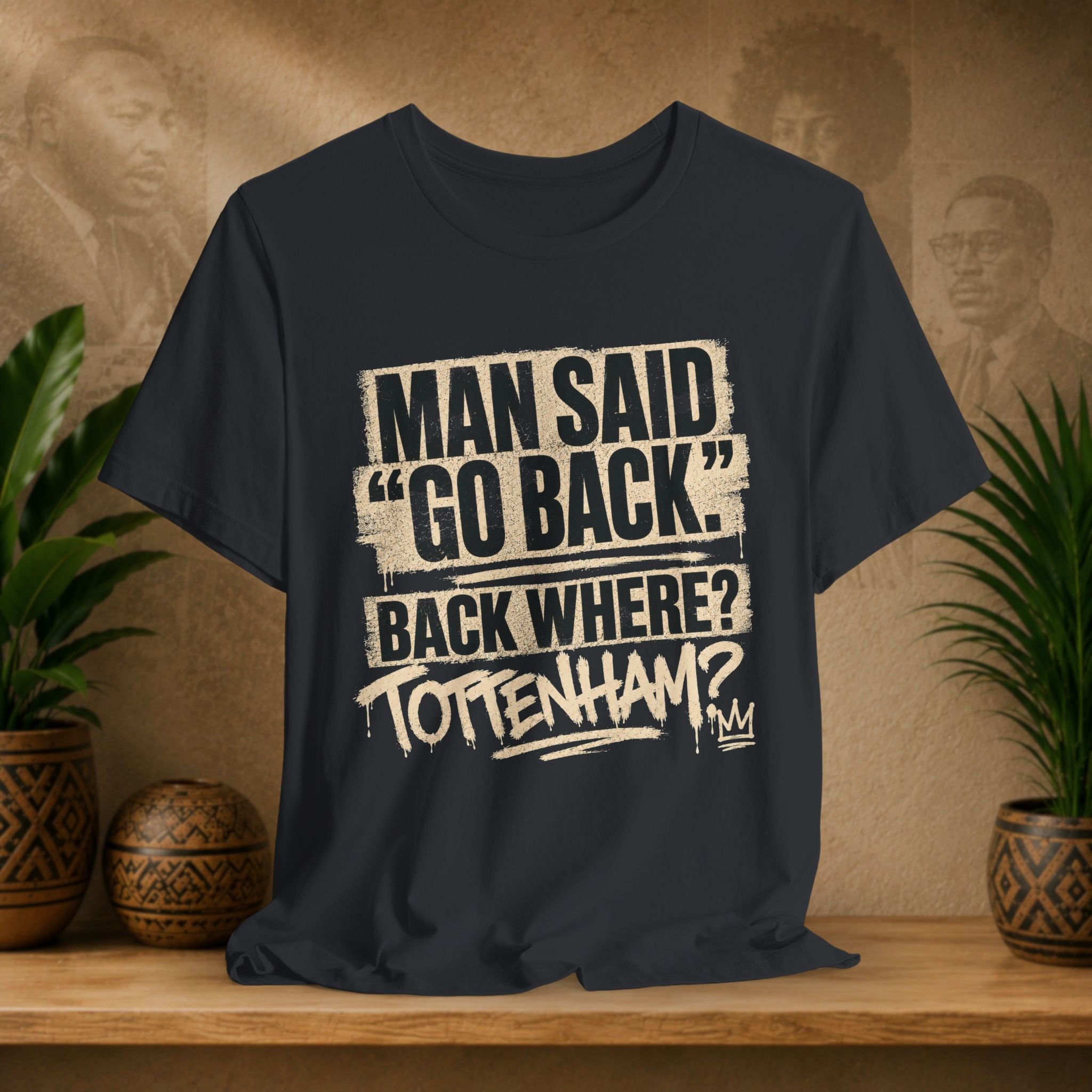 Black t-shirt with humorous text design on a wooden surface with plants and a textured wall background