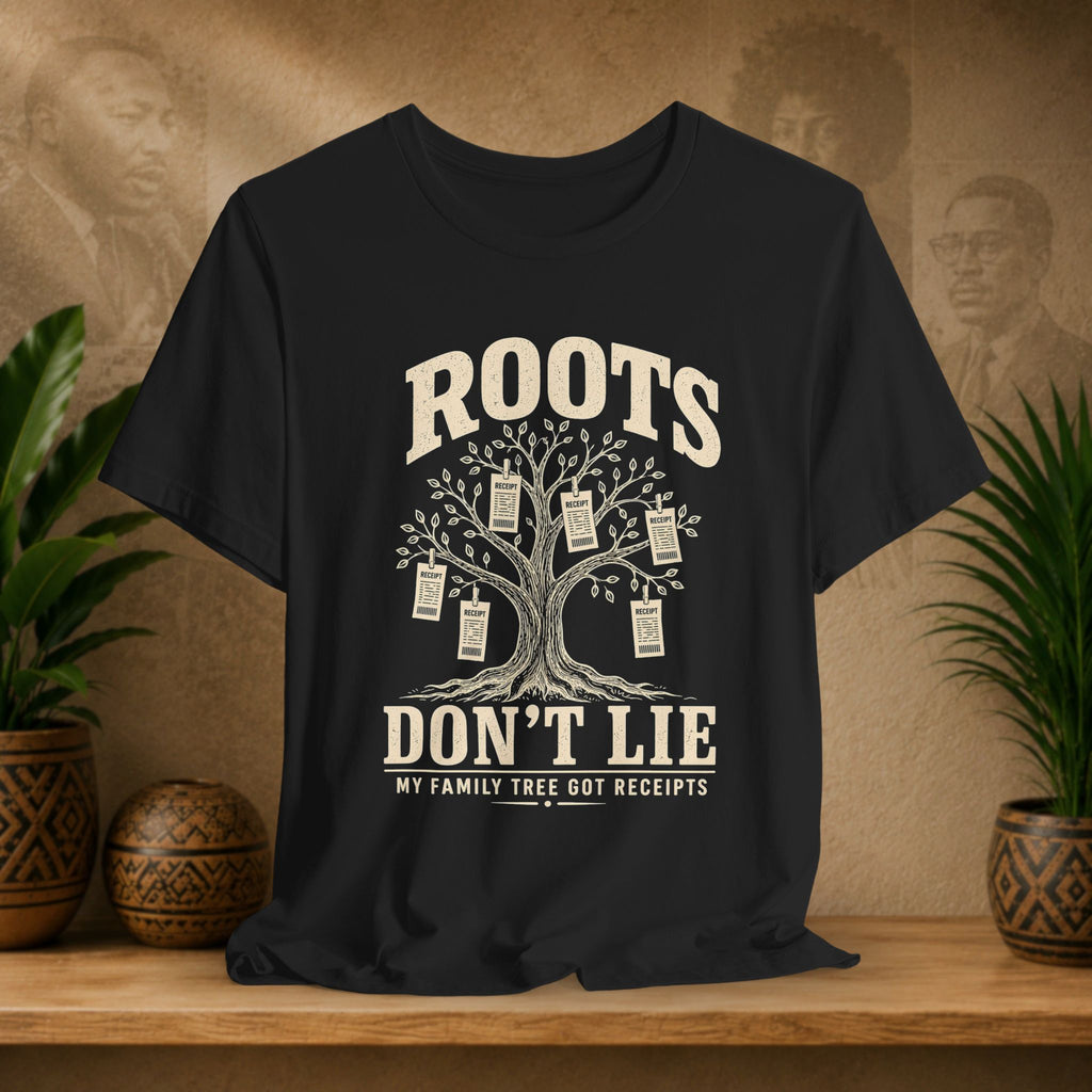 Black t-shirt with a family tree graphic and text on a wooden surface with plants and decorative items.