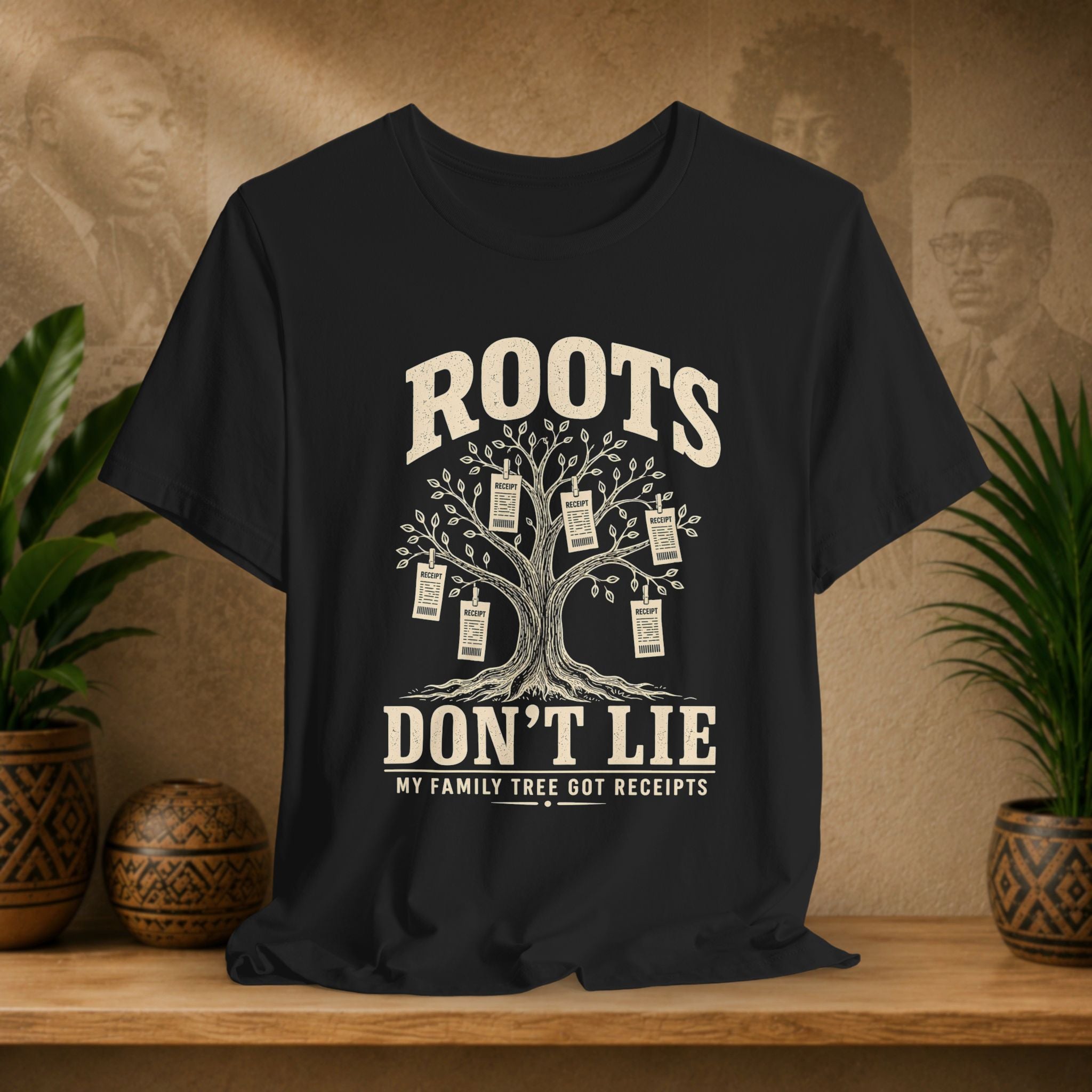 Black t-shirt with a family tree graphic and text on a wooden surface with plants and decorative items.
