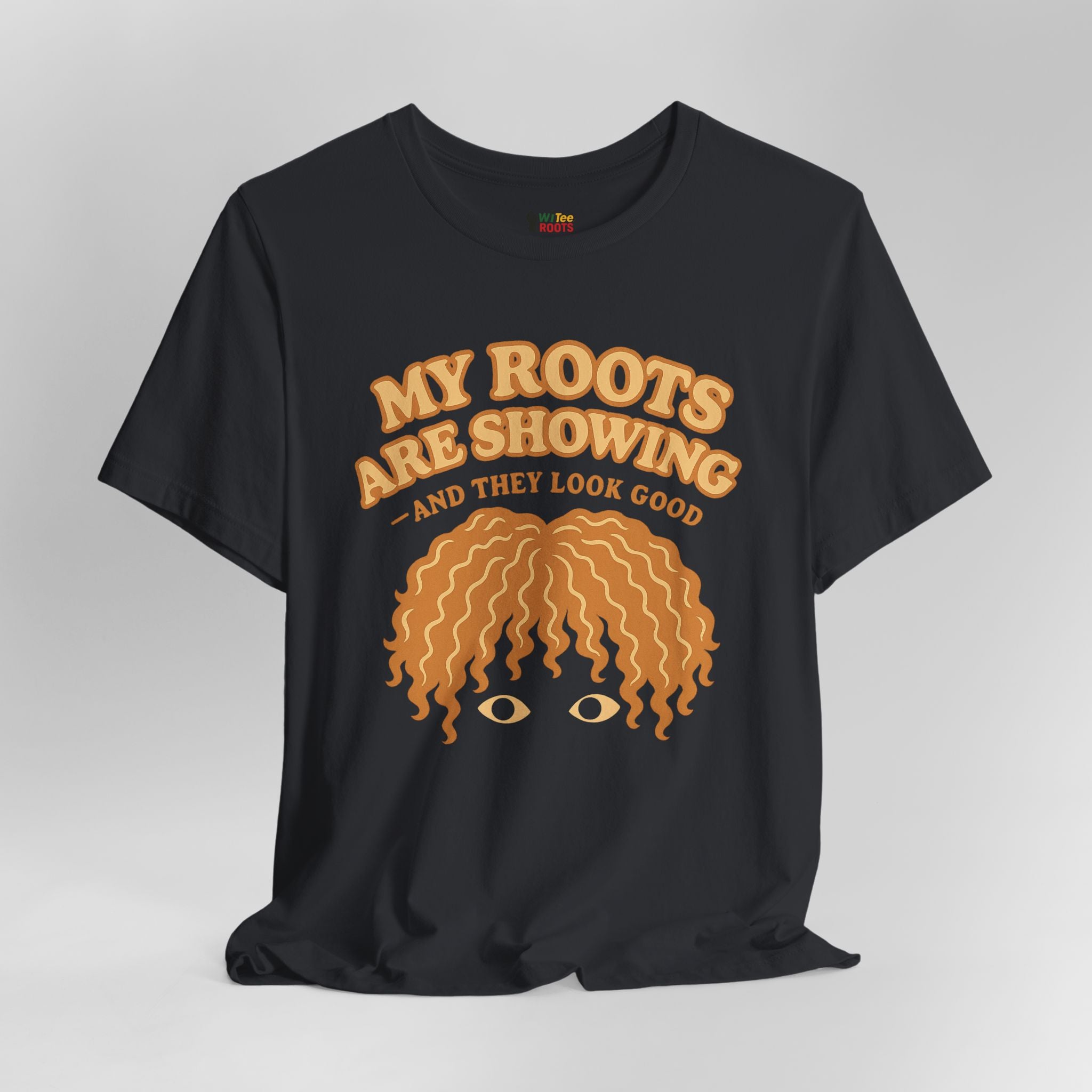 Black t-shirt with yellow graphic and text 'My roots are showing and they look good' on a gray background