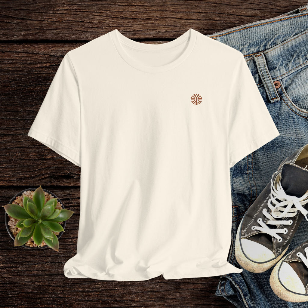 Beige t-shirt with a logo on a wooden surface with jeans and sneakers.