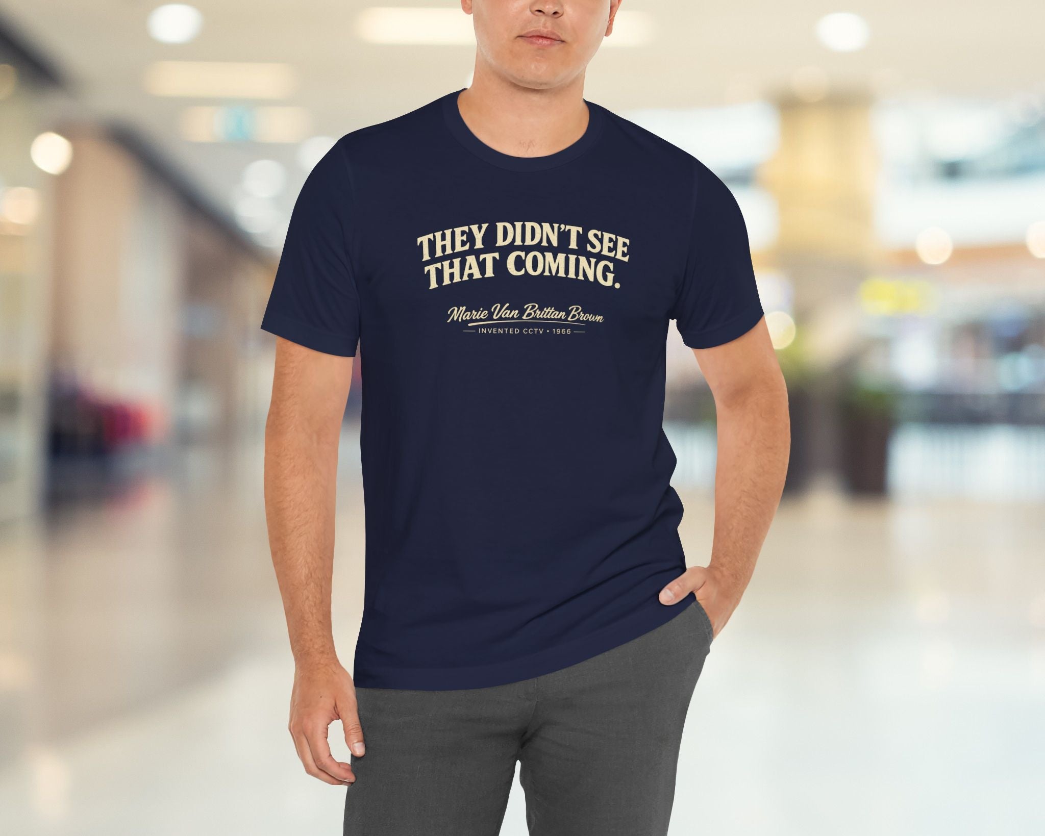 Man wearing a navy blue t-shirt with text in a blurred indoor setting