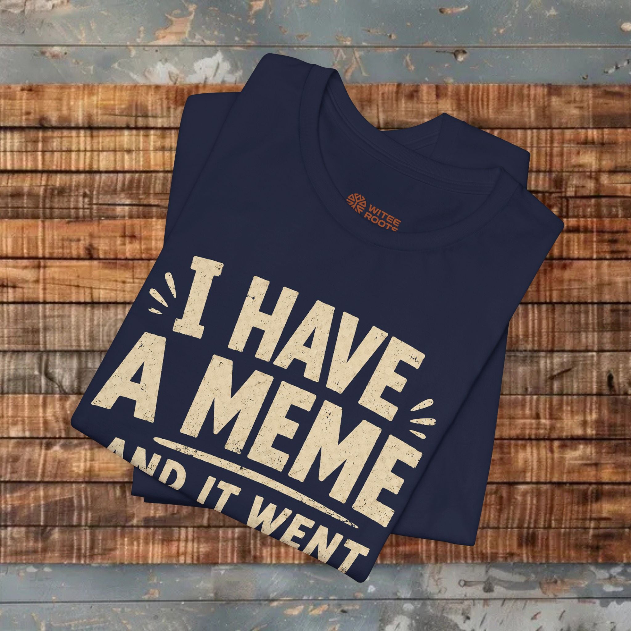 Folded navy blue t-shirt with 'I have a meme and it went' text on a wooden surface