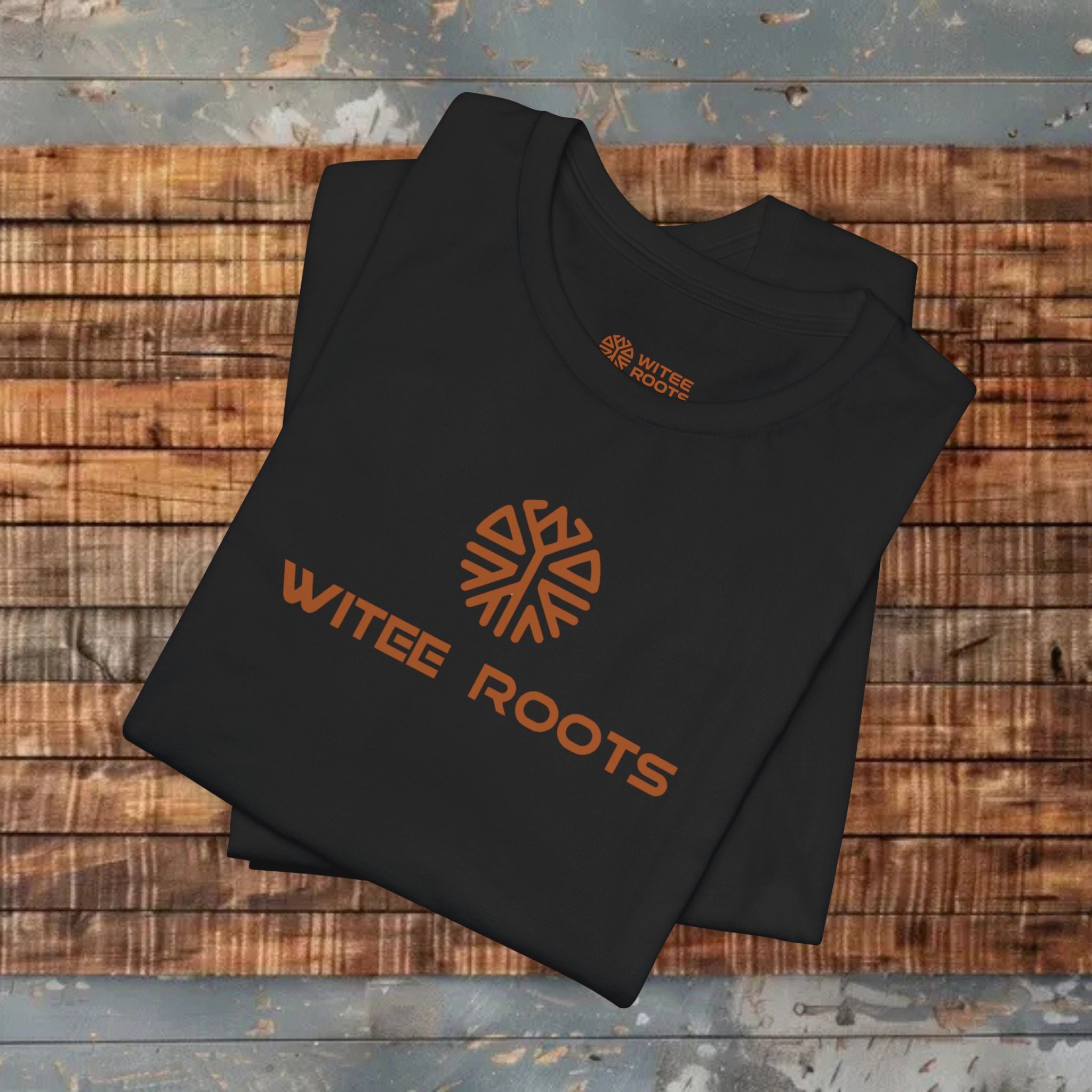 Black t-shirt with 'WITEE ROOTS' logo on a wooden surface