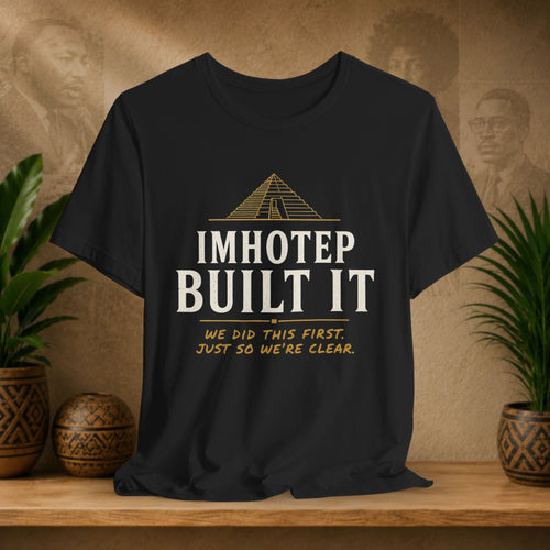 Black t-shirt with 'IMHOTEP BUILT IT' text on a wooden surface with decorative items.