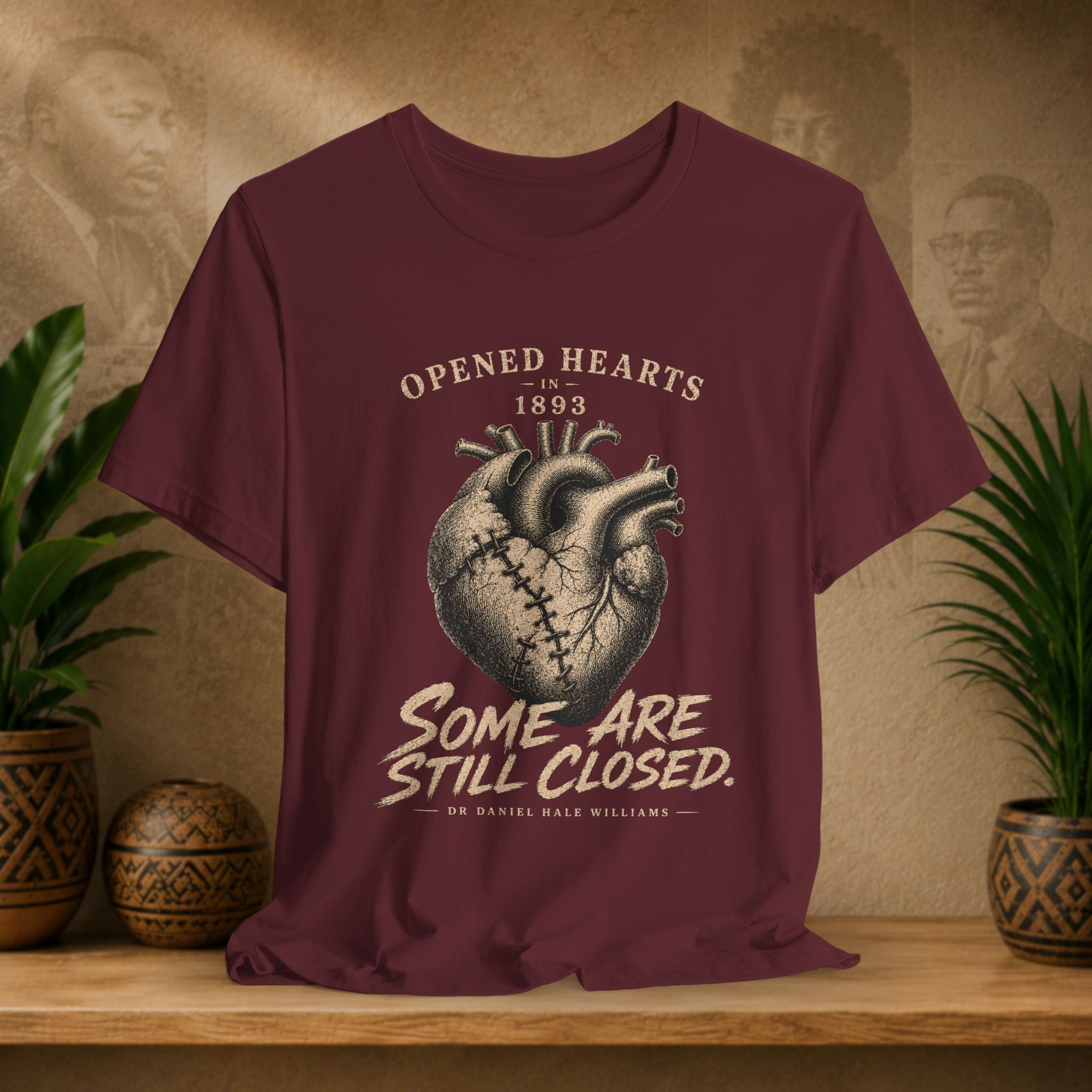 Maroon t-shirt with heart design and text on a wooden surface with plants and decorative items.