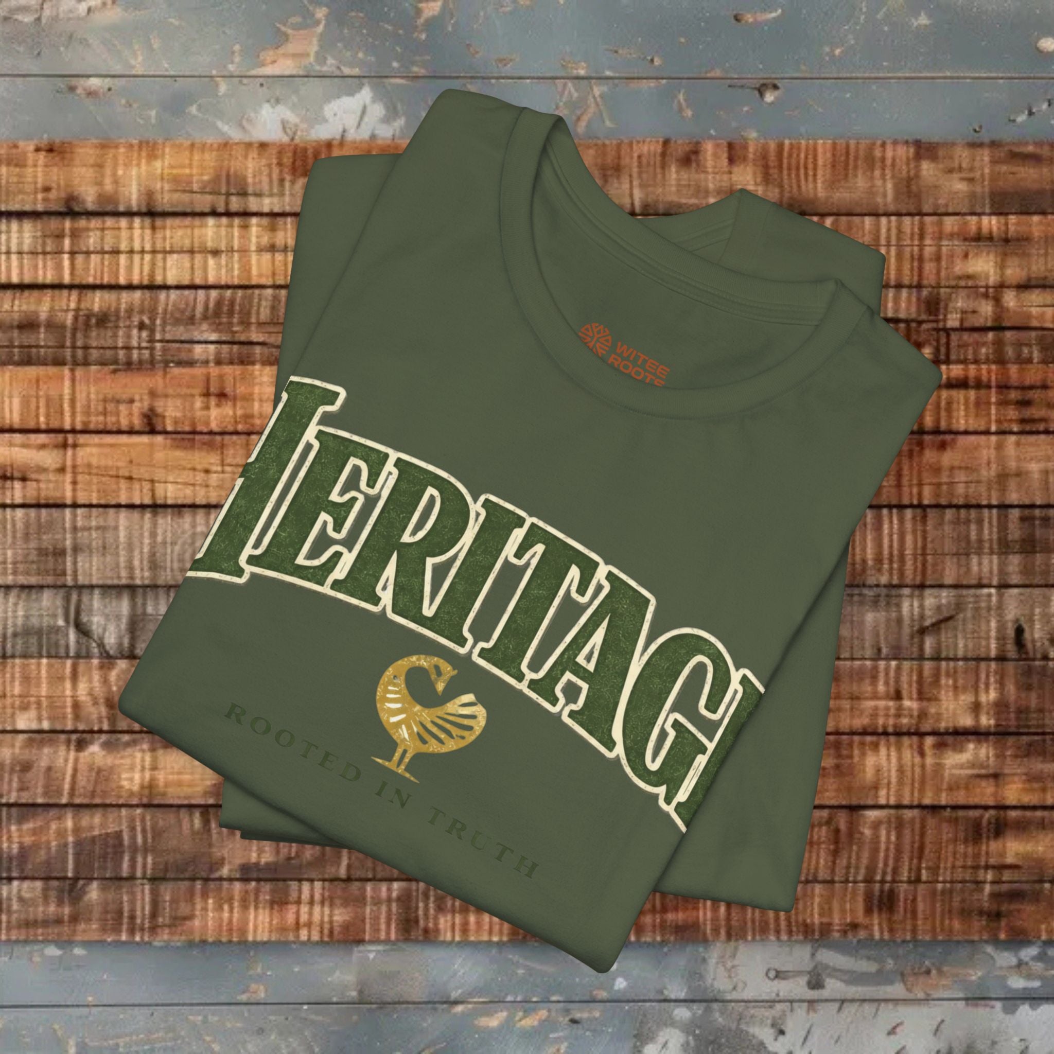 Folded green t-shirt with 'Heritage' text on a wooden surface