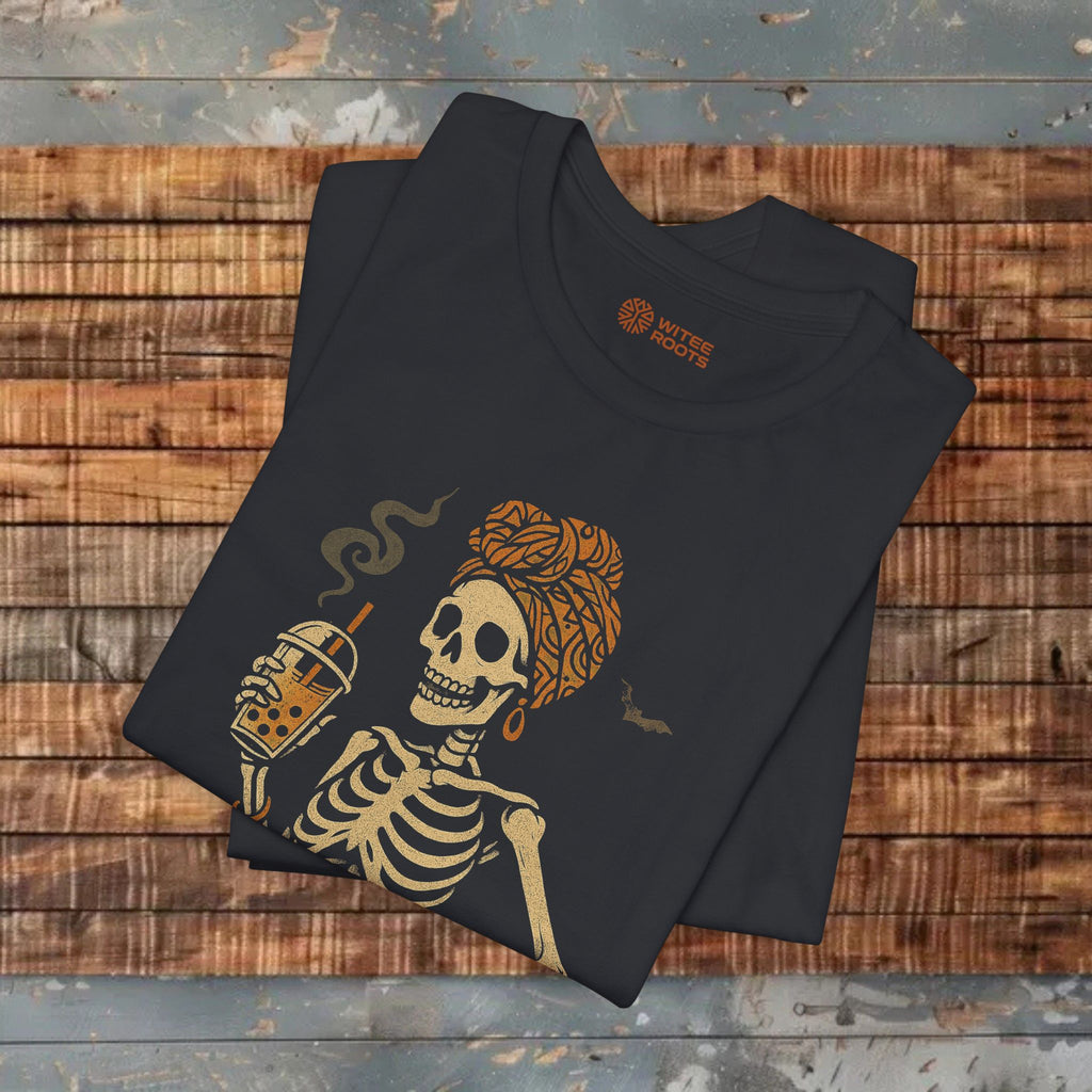 A folded black t-shirt with a graphic of a skeleton holding a bubble tea cup, displayed on a rustic wooden plank background. The inner collar shows the brand name 'SILK ROUTE'.