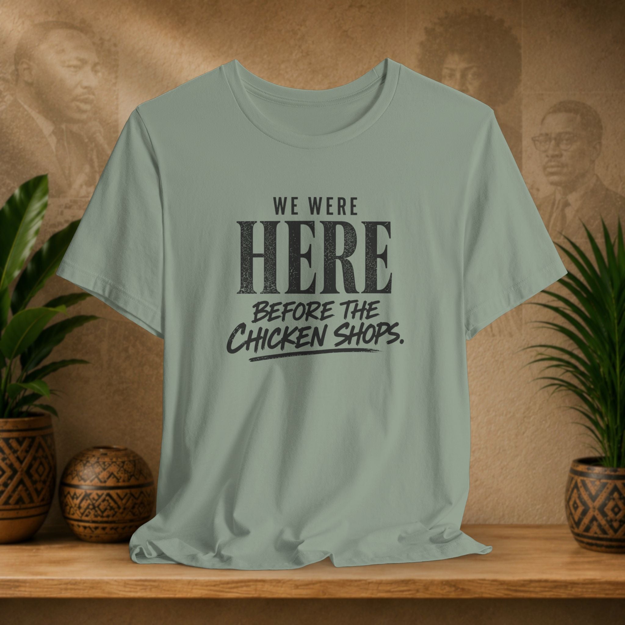 Green t-shirt with text on a wooden surface with plants and a textured wall background