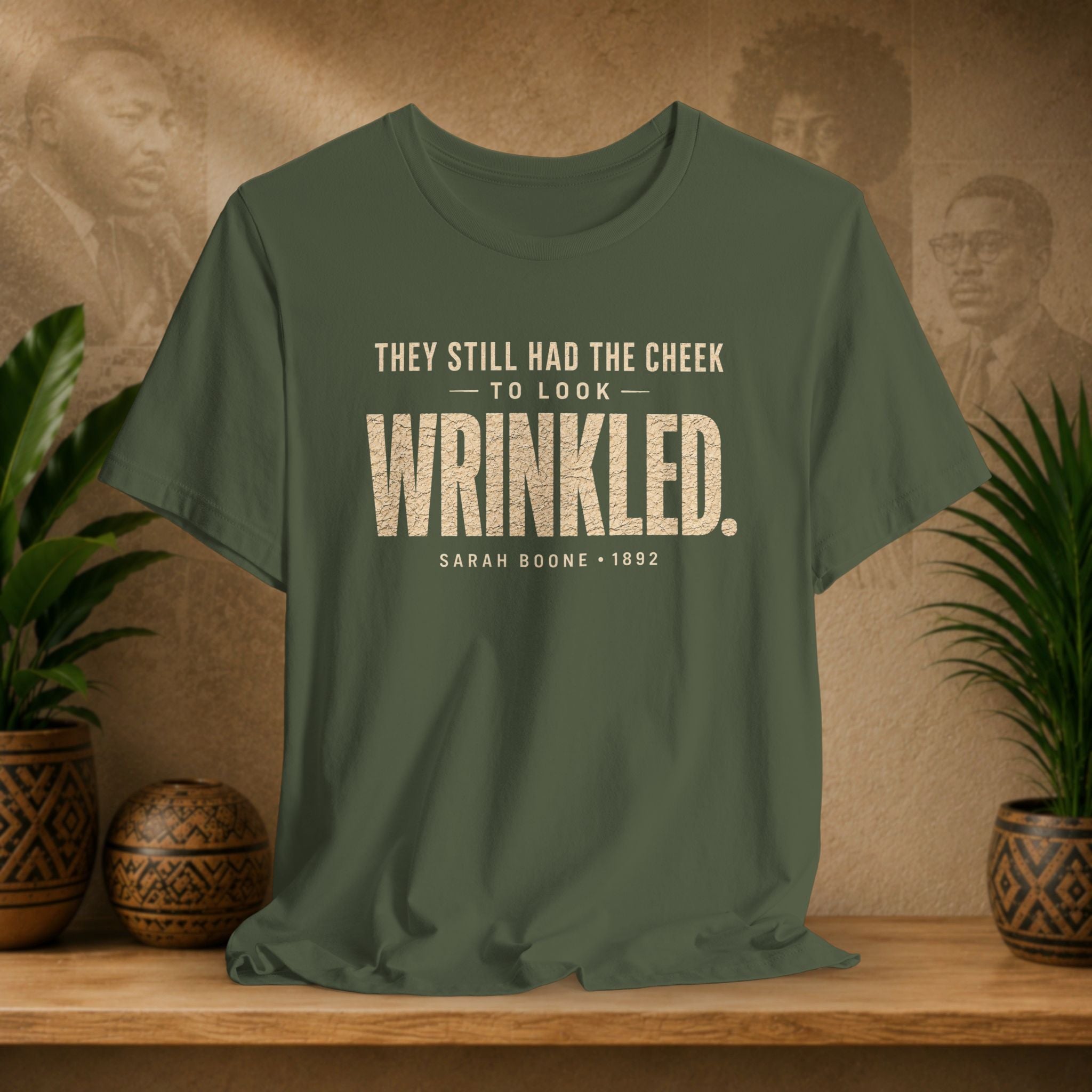 Green t-shirt with text on a wooden surface with plants and a textured wall background