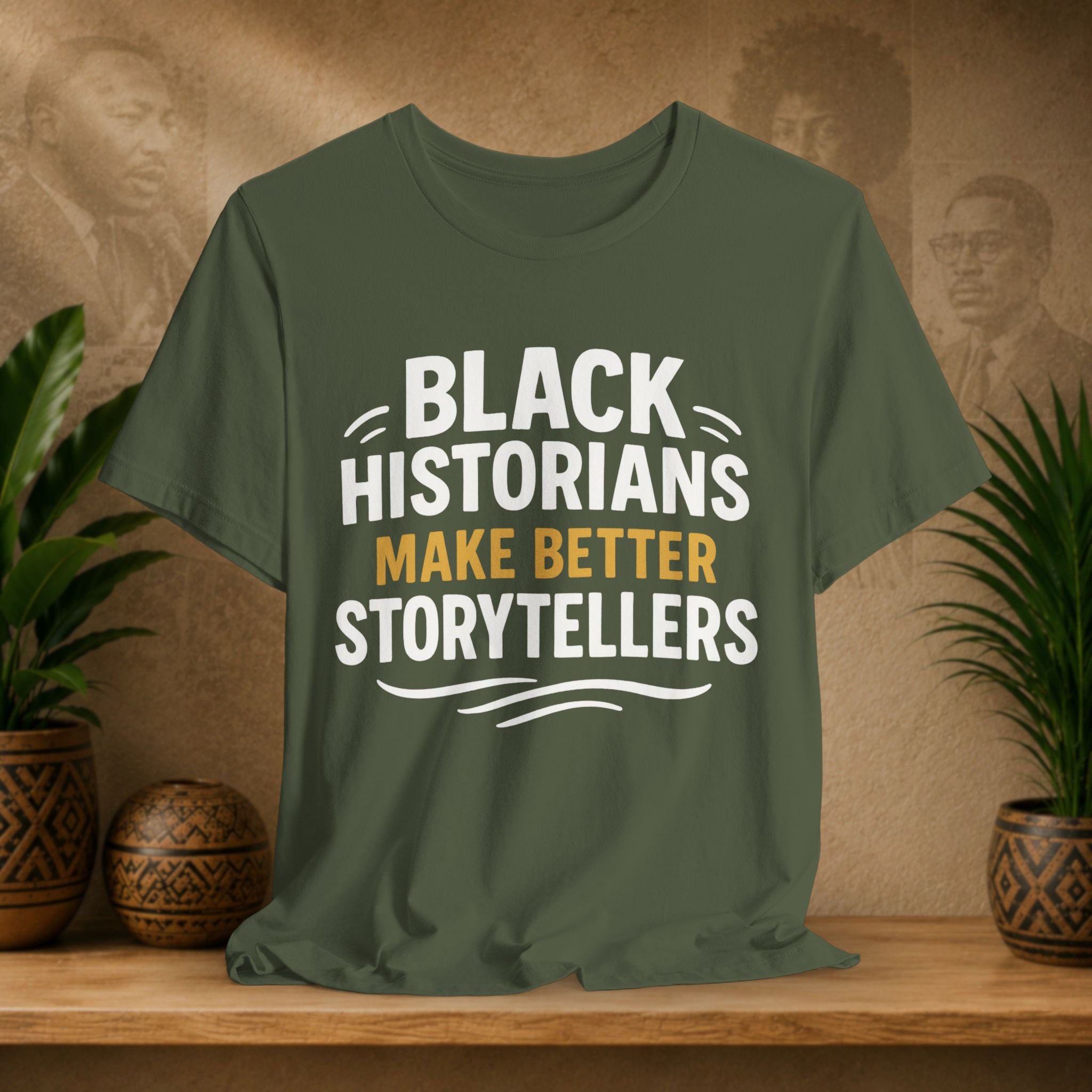 Green t-shirt with 'Black Historians Make Better Storytellers' text on a wooden surface with decorative items.