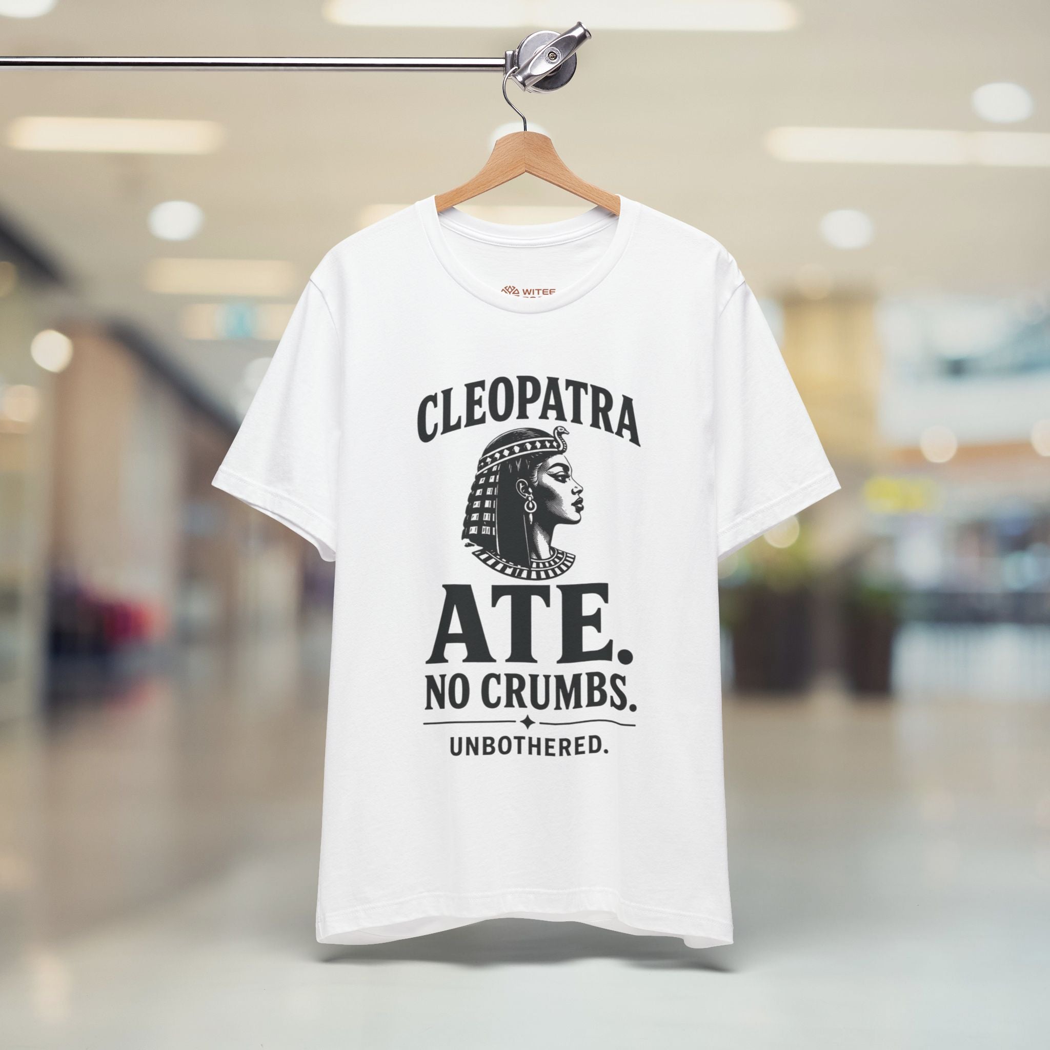 White t-shirt with black text and graphic on a hanger in a store setting