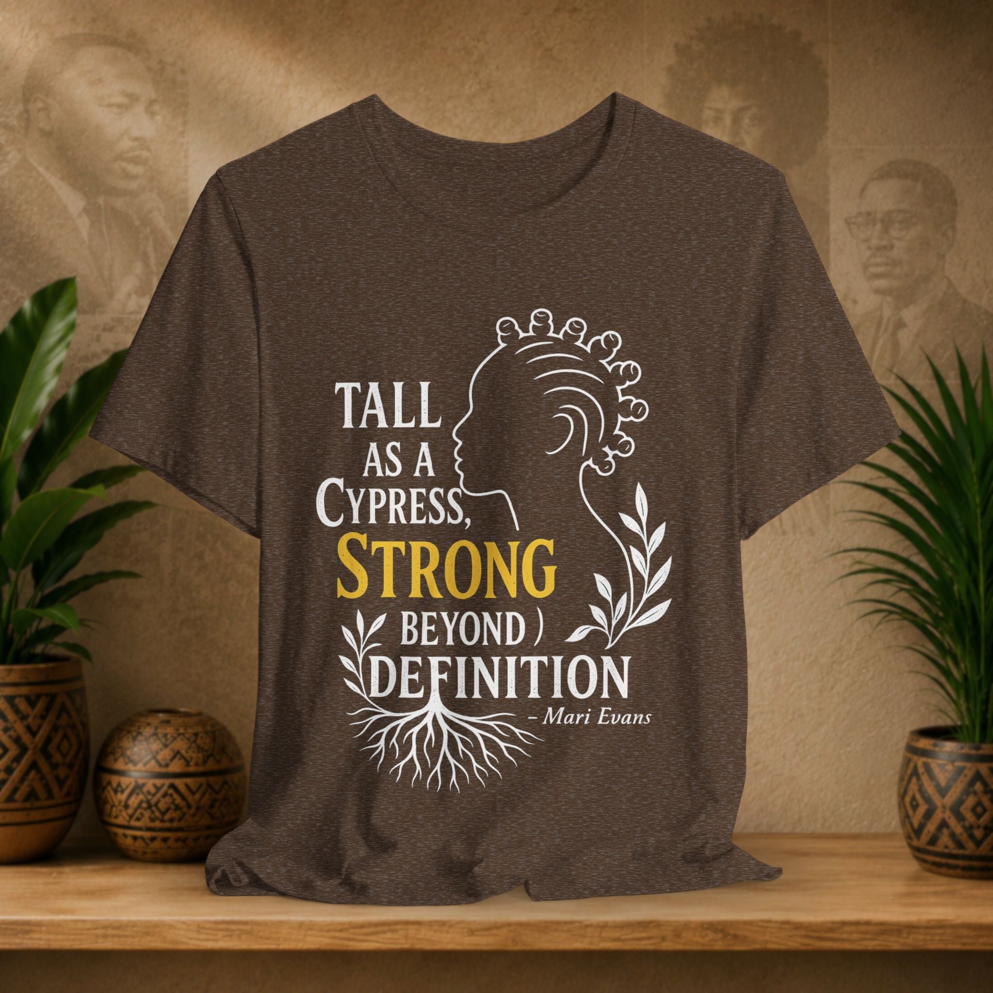 Brown t-shirt with motivational quote on a wooden shelf with plants and decorative items.