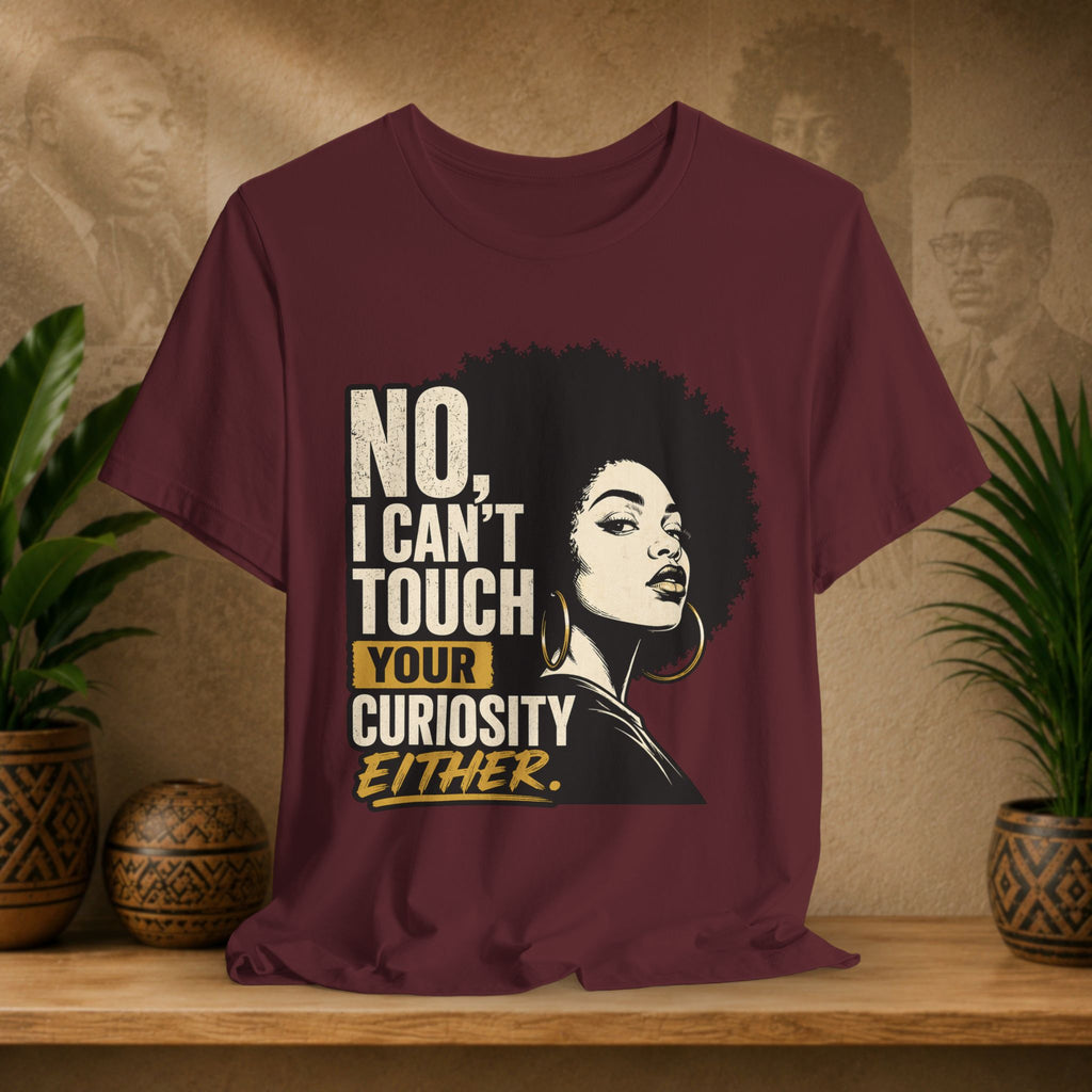 Maroon t-shirt with graphic and text on a wooden surface with plants and wall art in the background